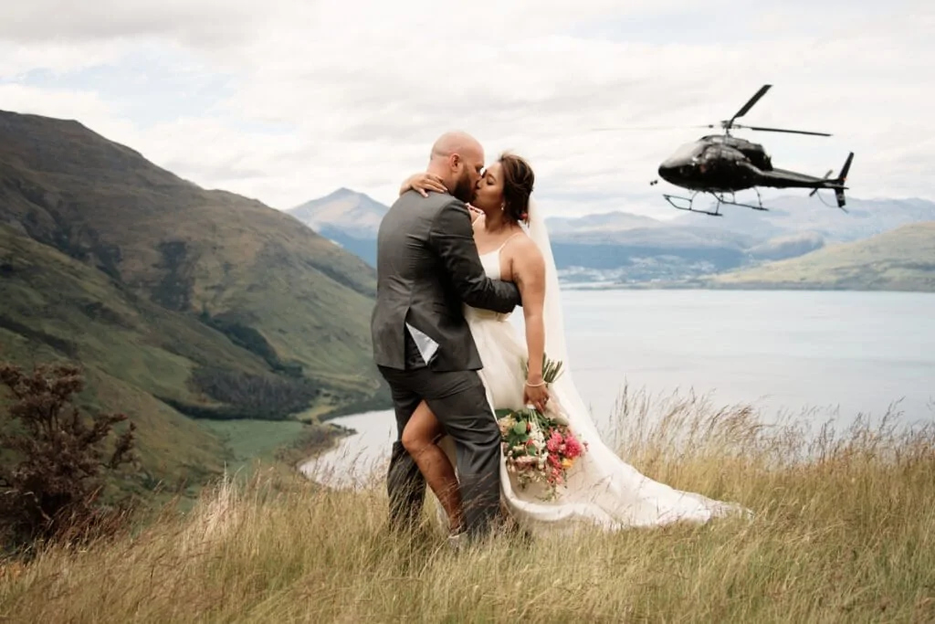 June and Mark share a romantic kiss during their Queenstown Heli Wedding, with the stunning helicopter as their backdrop for unforgettable previews.