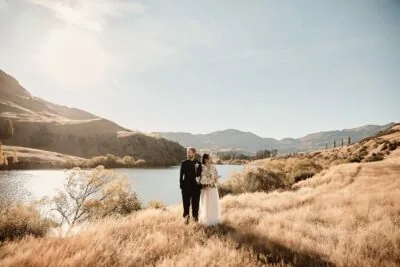 Ayaka Morita's portfolio showcases a couple, the bride and groom, standing near a lake surrounded by vibrant green grass.