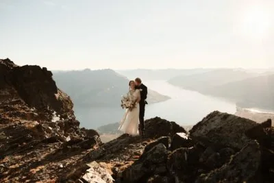 A bride and groom on a cliff overlooking a lake captured in Ayaka Morita's portfolio.