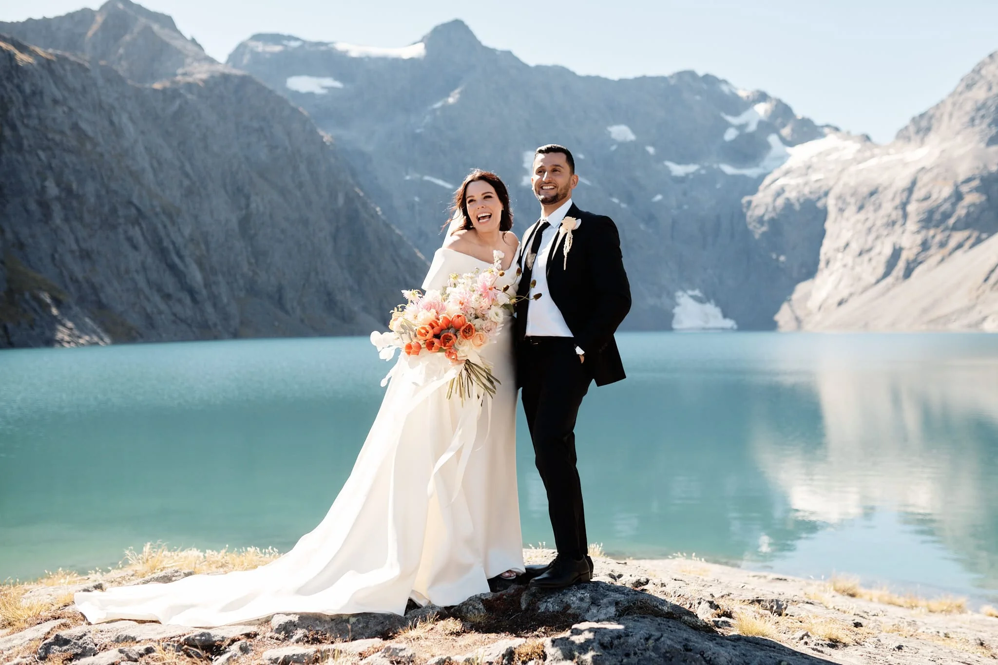 A bride and groom standing in front of mountains.