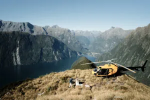 Josh Yates - Portfolio: A helicopter perched on a mountain surveys a lake.