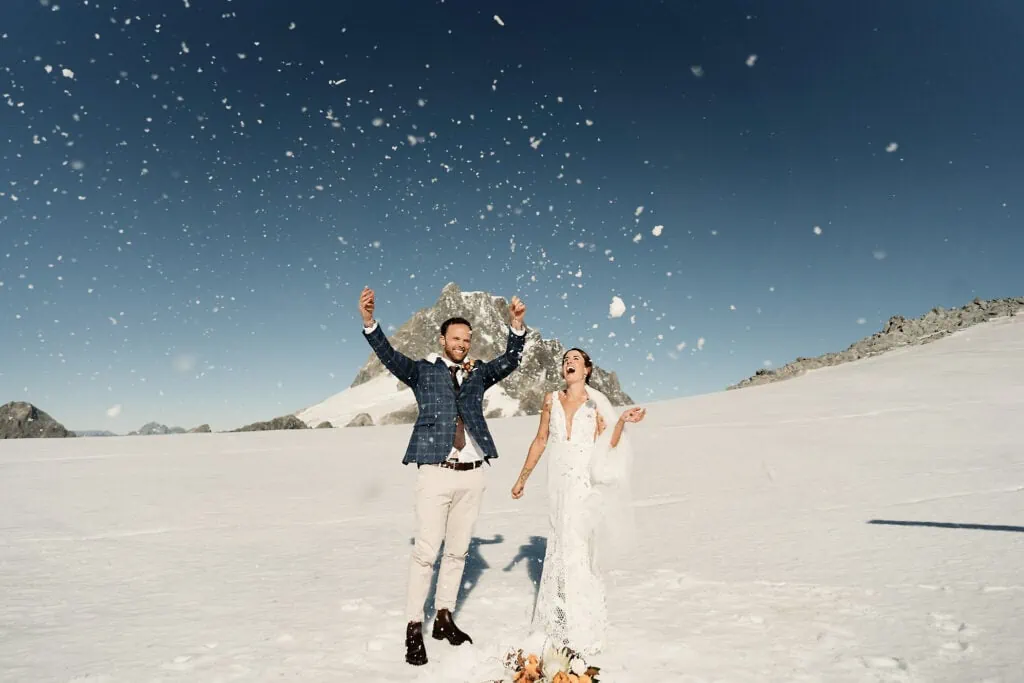 A bride and groom playfully throwing snow at each other, captured beautifully in Josh Yates' portfolio.