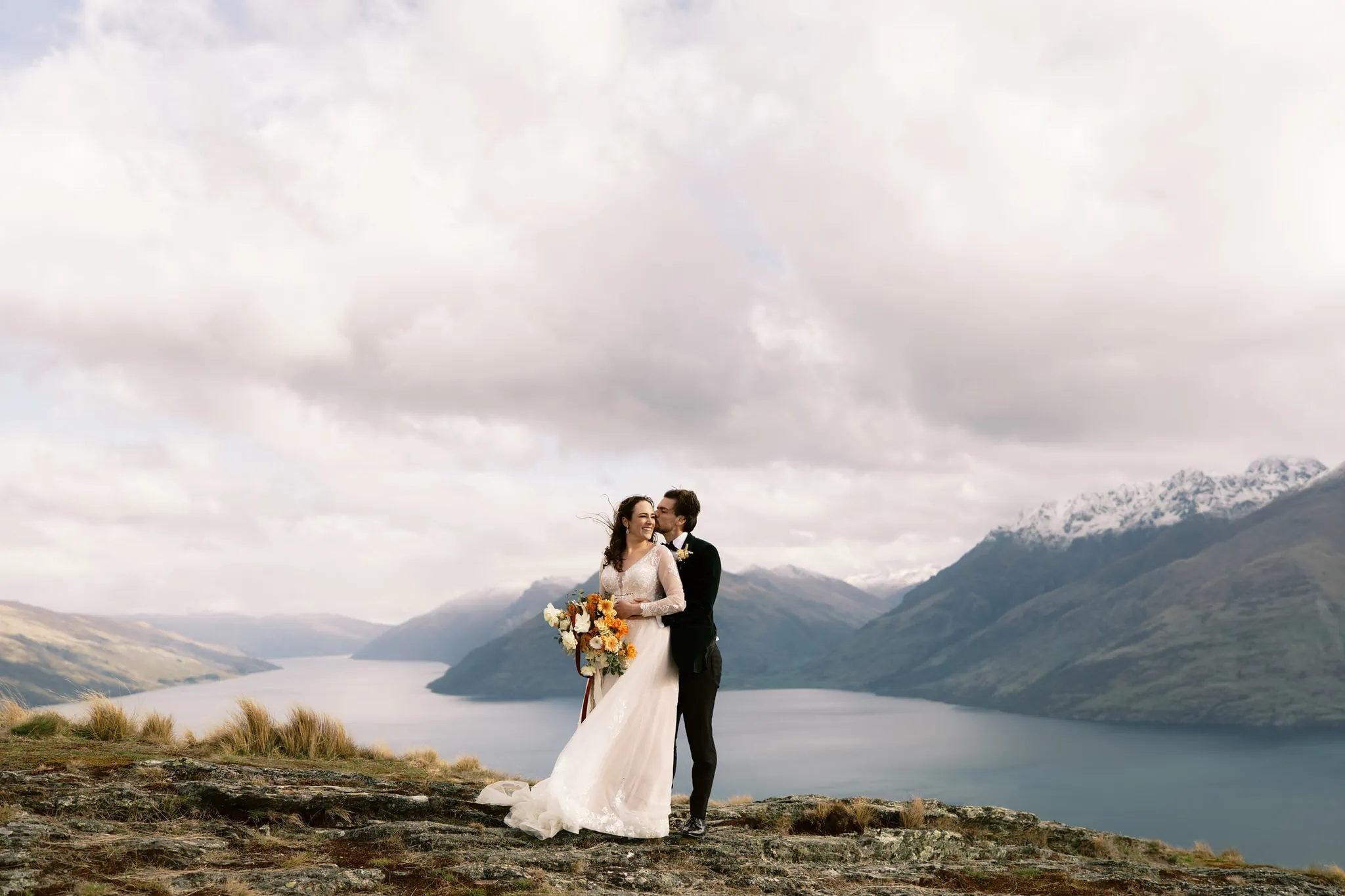 Queenstown New Zealand Elopement Wedding Photographer - photograph of a bride and groom standing on top of a mountain overlooking Lake Wakatipu, at Deer Park Heights