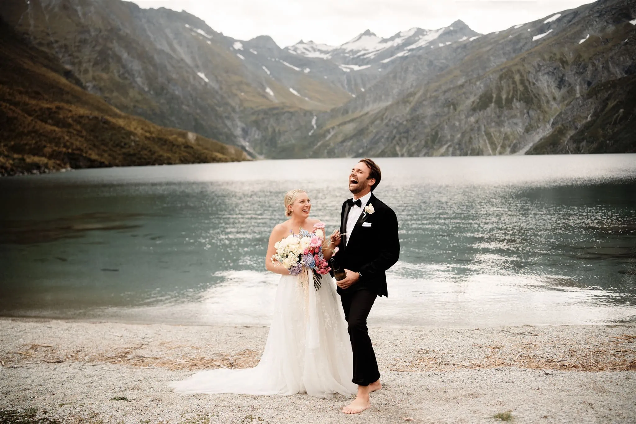  Queenstown Wedding Photographer takes stunning photos of a bride and groom in front of a lake in New Zealand.