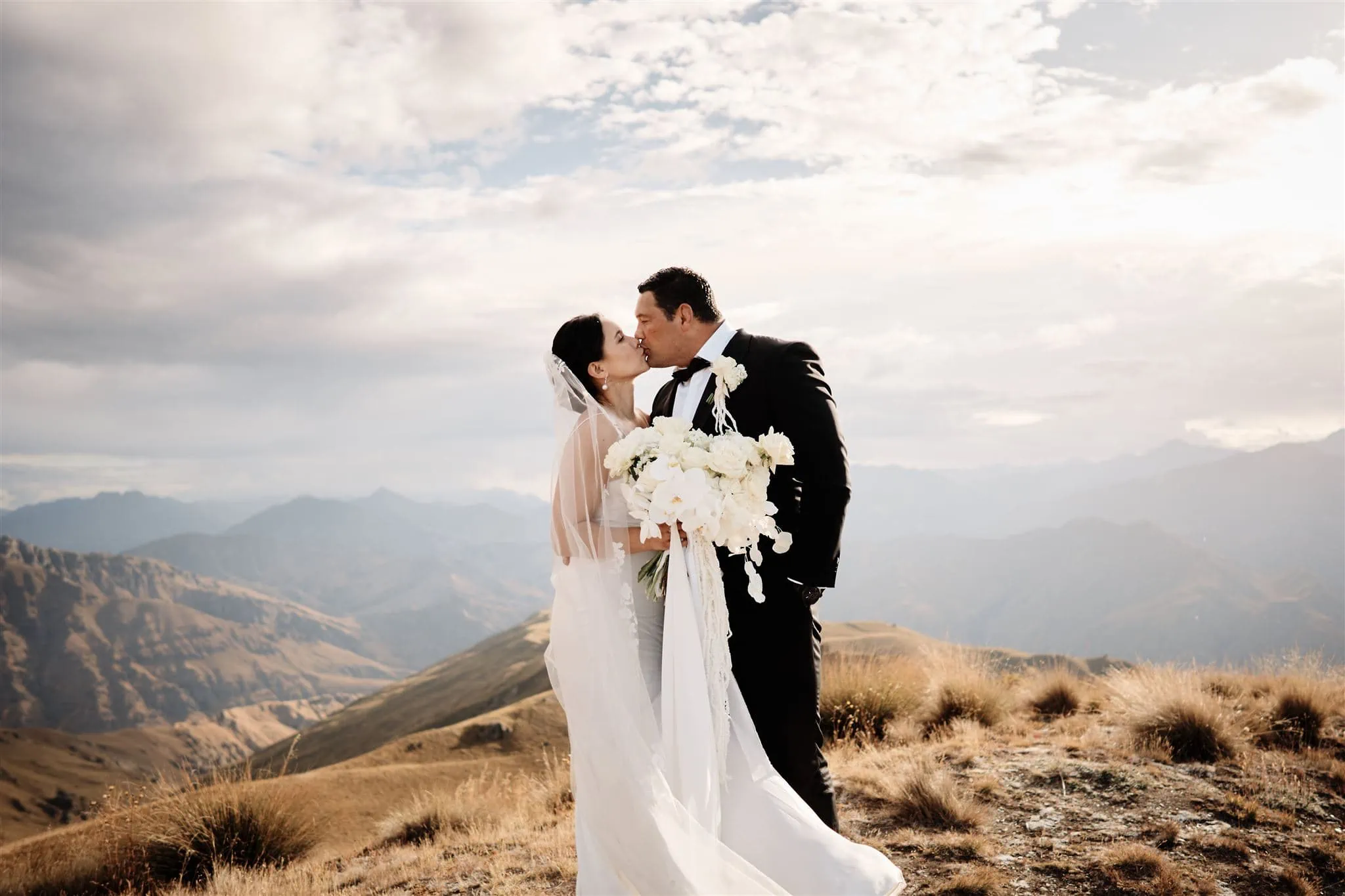 Queenstown New Zealand Elopement Wedding Photographer - A bride and groom kissing on top of Vanguard Peak in New Zealand