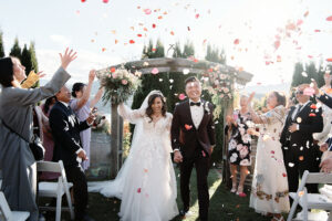 Josh Yates - Portfolio: An entrancing capture of a bride and groom gracefully strolling through a confetti-filled aisle.