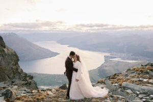 Josh Yates - Portfolio: A bride and groom embrace on a mountaintop near Lake Wanaka.