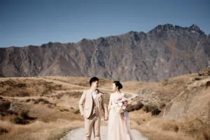 A bride and groom on a dirt road with mountains in the background captured by Josh Yates for his portfolio.