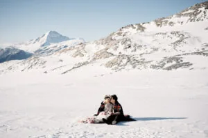 Josh Yates' portfolio featuring a couple sitting on the snow with a mountain backdrop.