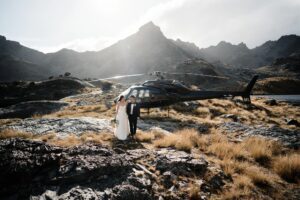 FAQ's: A couple next to a helicopter in the mountains on their wedding day.