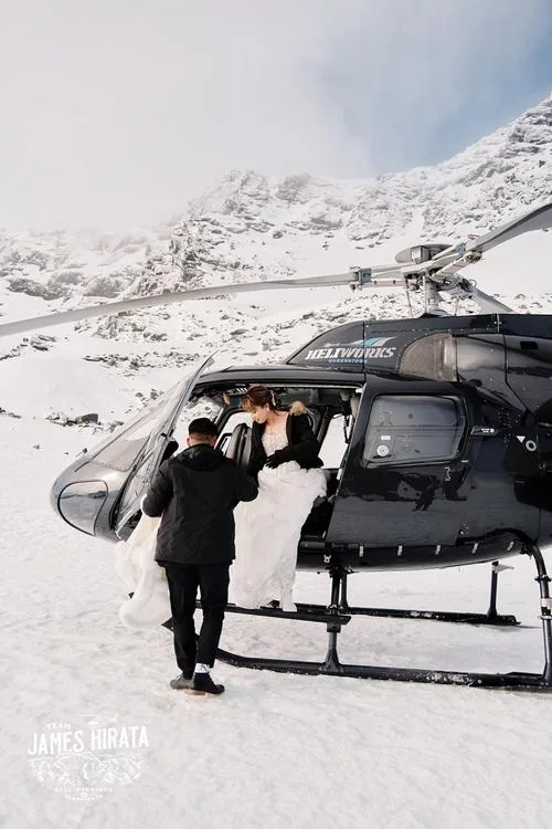 A Queenstown Heli Pre Wedding Shoot captures Joan and Brandon exiting a helicopter in the snowy landscape.