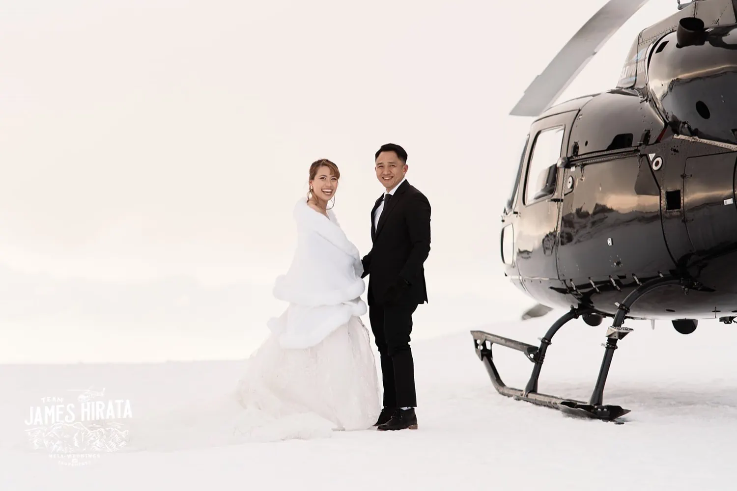 Joan & Brandon capture a memorable moment during their Queenstown Heli Elopement, standing in front of a helicopter.