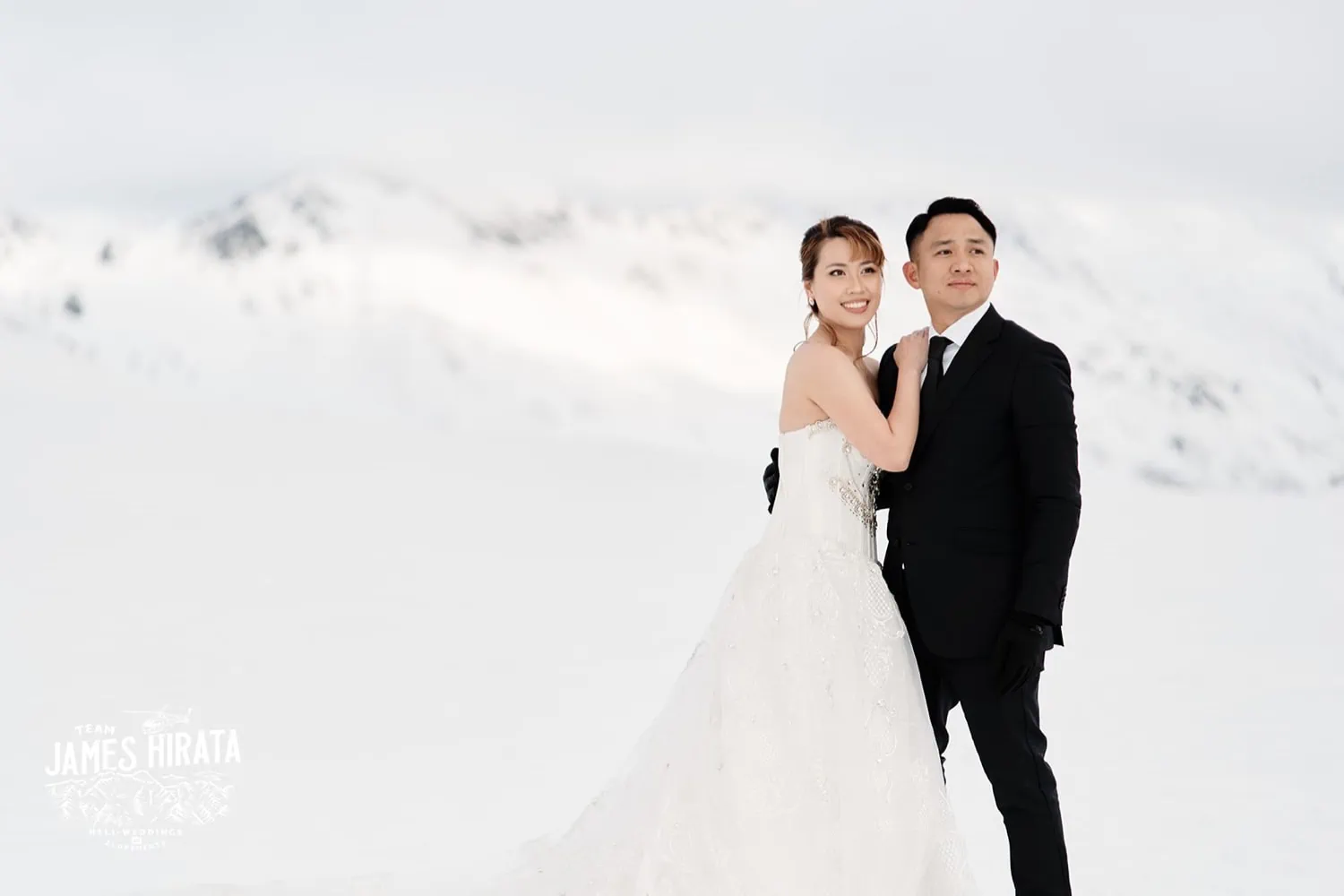 Joan and Brandon posing for a photo in the snow during their Queenstown Heli Pre Wedding Shoot.