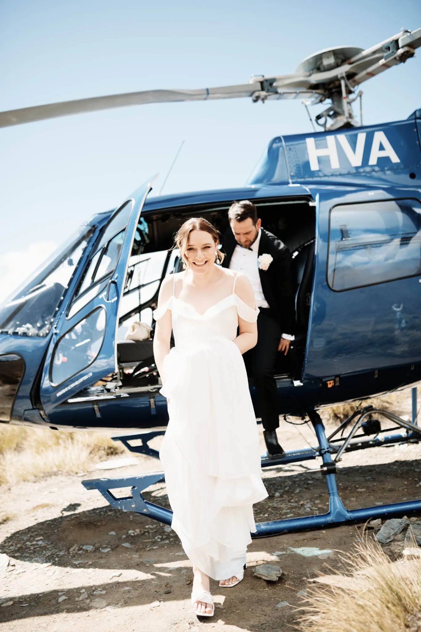 A Sapphire and JJ Queenstown Heli Elopement Wedding with a bride and groom standing next to a helicopter.