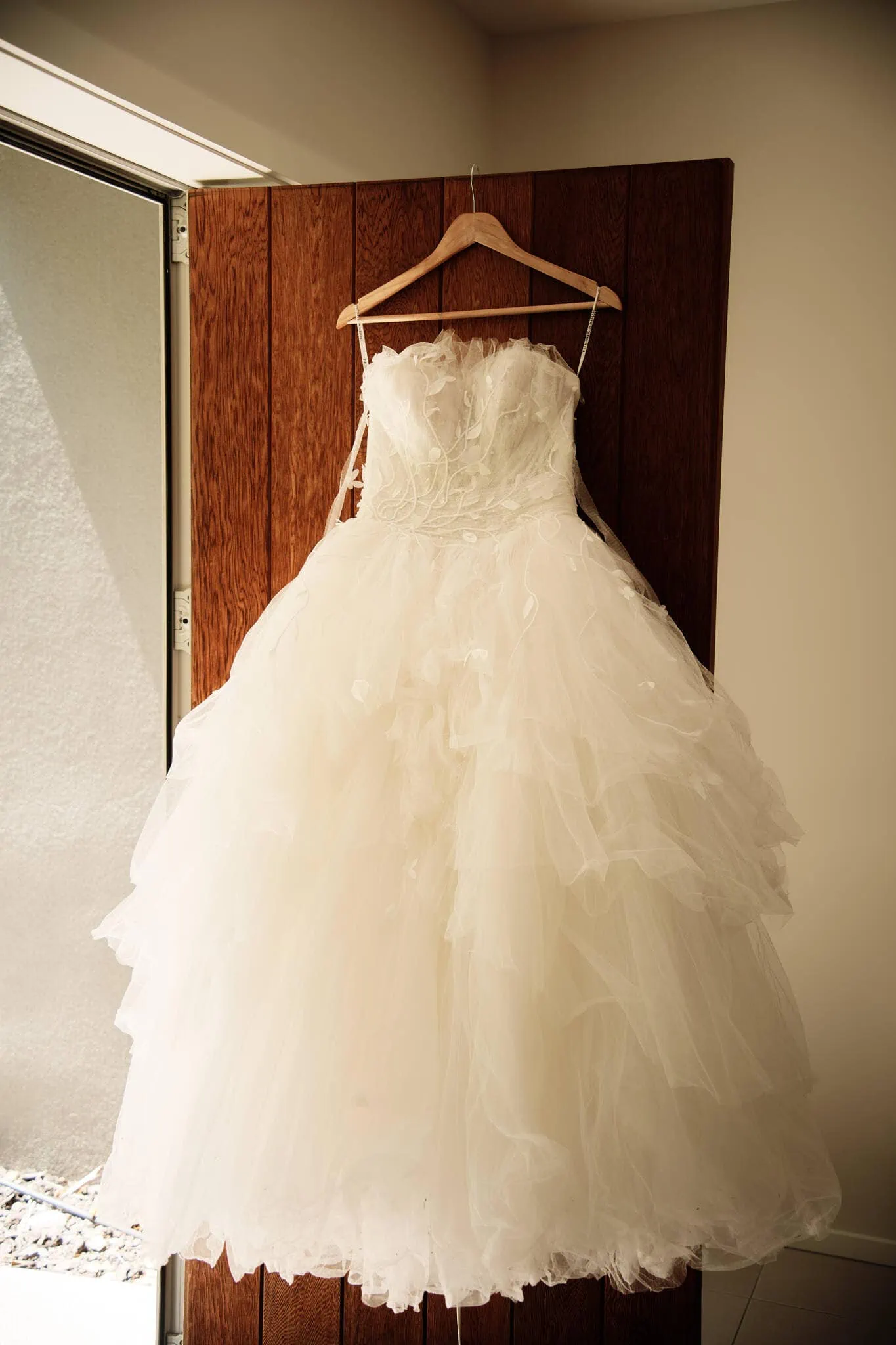 Carlos and Wanzhu's intimate wedding dress hanging on a wooden door.