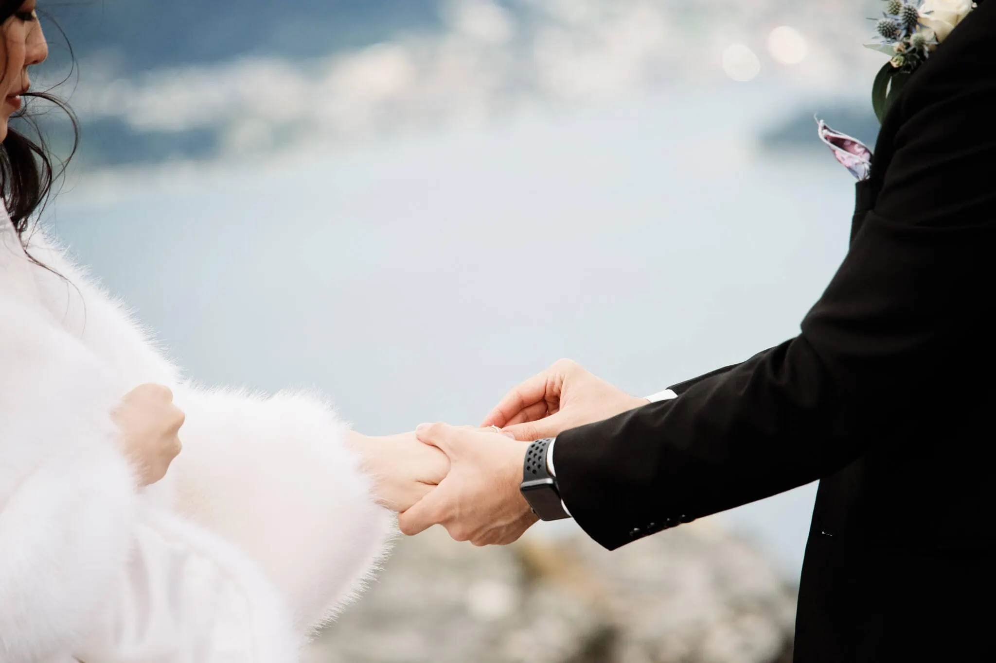 Carlos and Wanzhu's intimate wedding ceremony at Cecil Peak, holding hands in front of a lake.