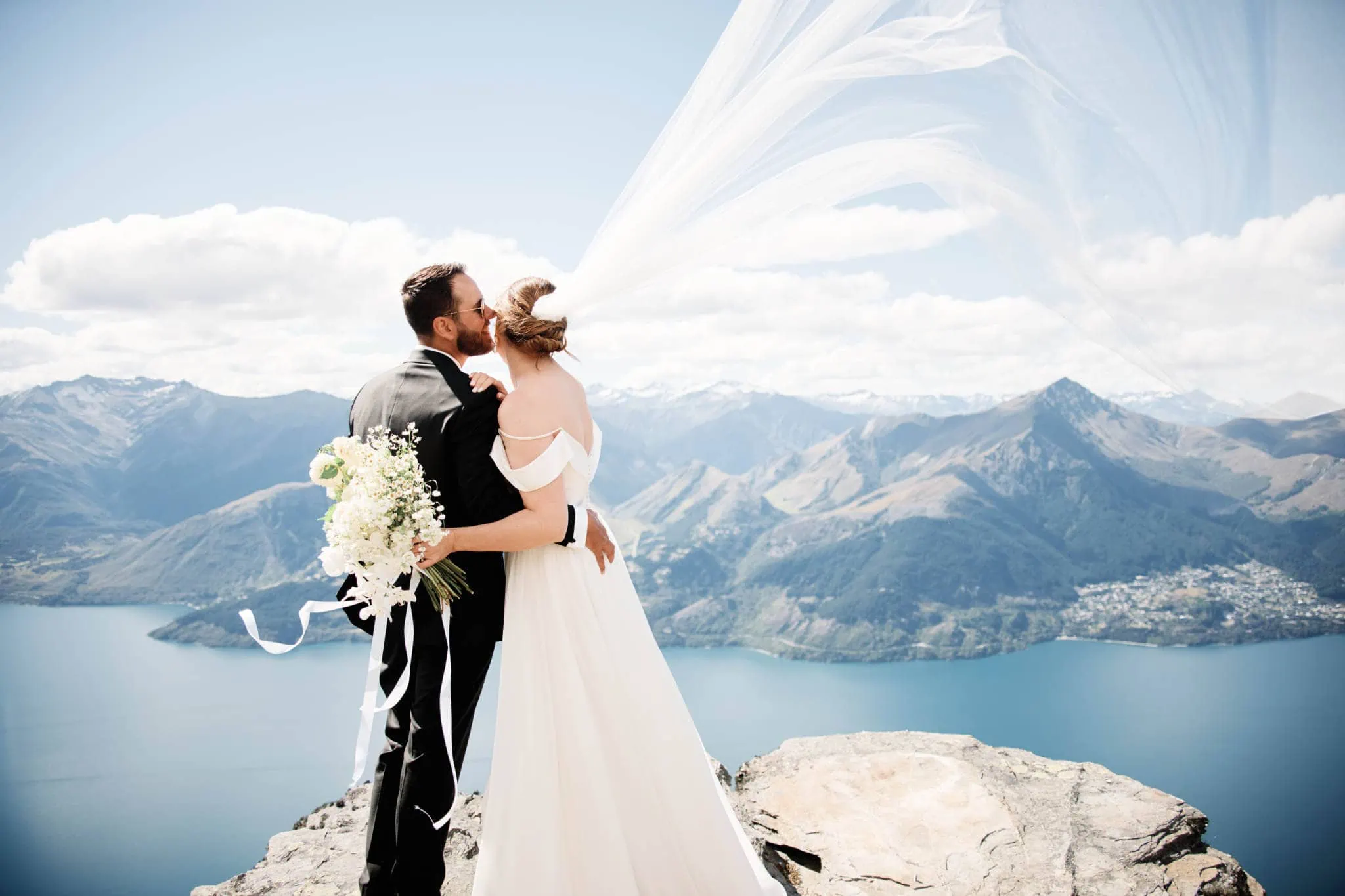 Sapphire and JJ celebrate their Queenstown Heli Elopement Wedding with a kiss on top of a mountain overlooking Lake Wanaka.
