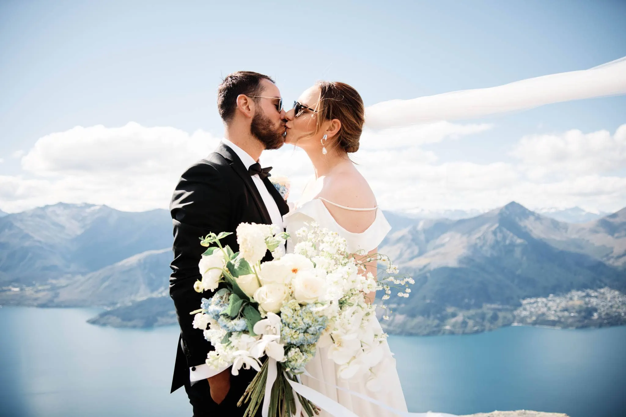 Sapphire and JJ have a Queenstown Heli Elopement Wedding, kissing on top of a mountain overlooking Lake Wanaka.