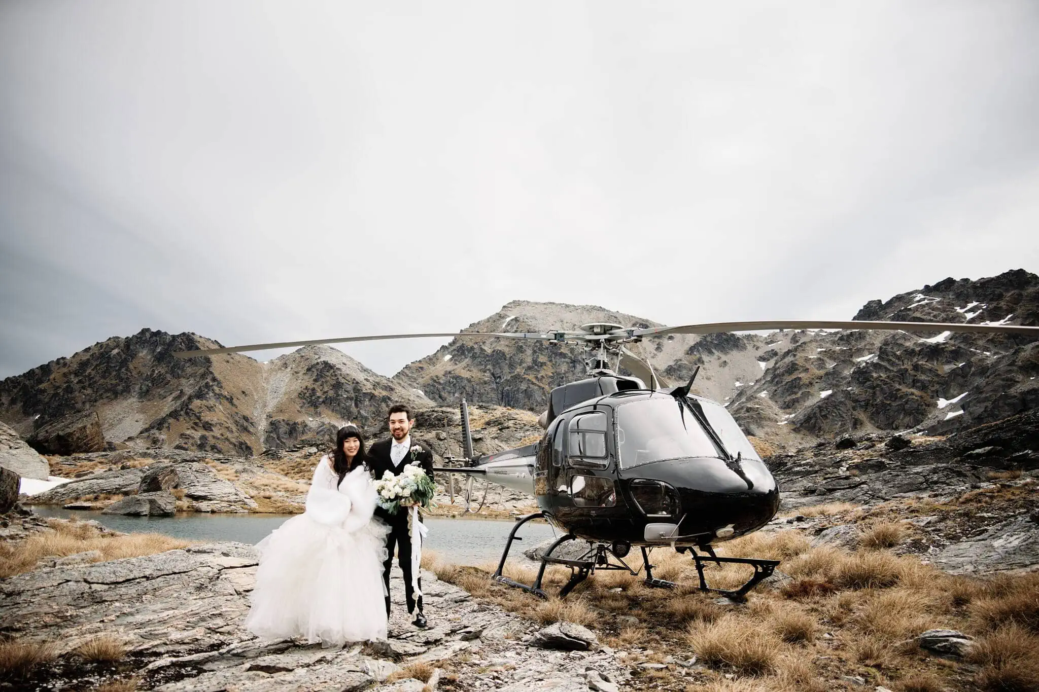 Carlos and Wanzhu's intimate elopement wedding, standing next to a helicopter in the mountains.