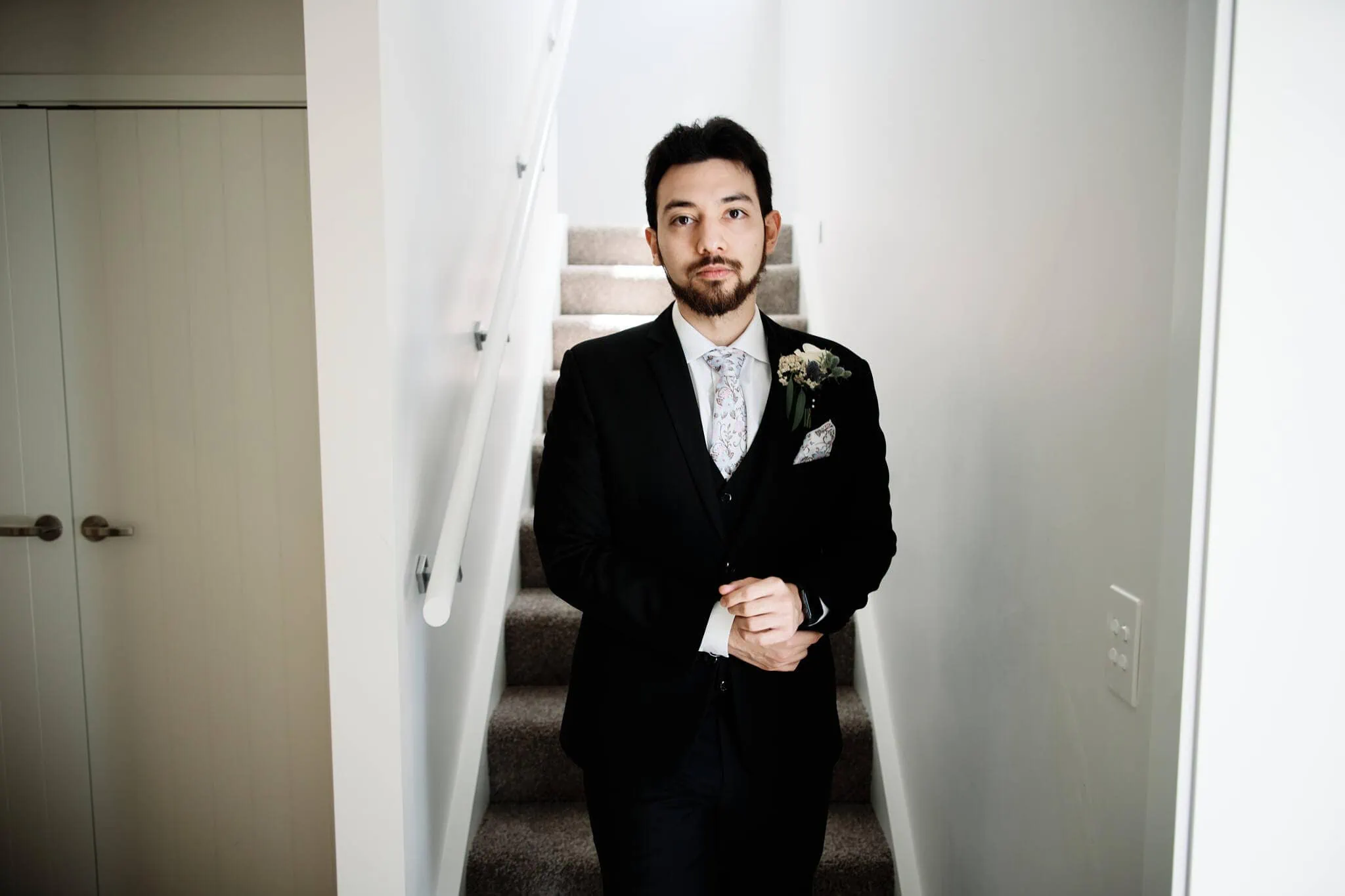 A man in a suit standing in a hallway at Carlos and Wanzhu's intimate Cecil Peak Heli Elopement Wedding.