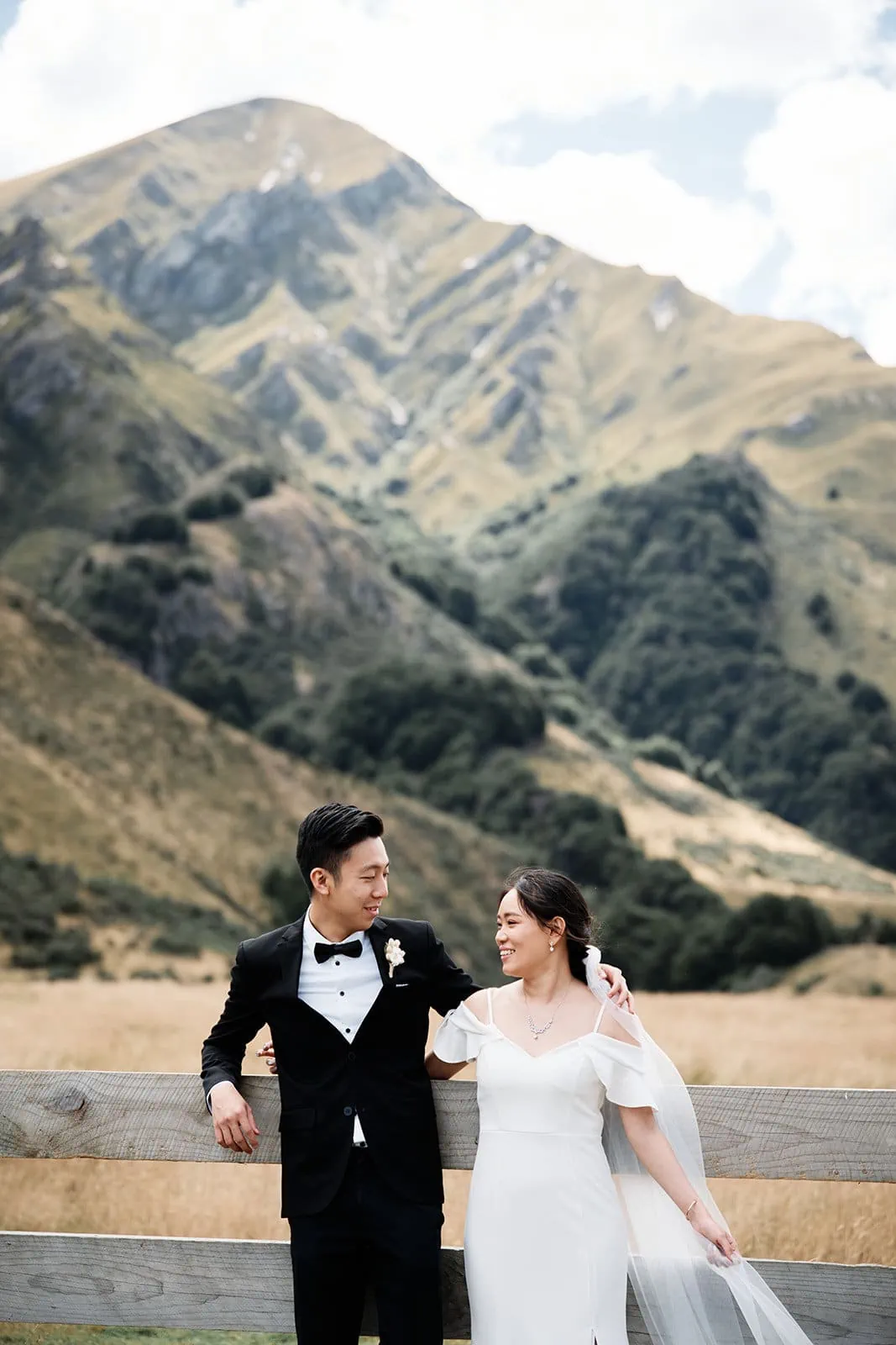 Dios & Carlyn's Queenstown Heli Pre Wedding at Cecil Peak captures a bride and groom standing in front of a majestic mountain backdrop.