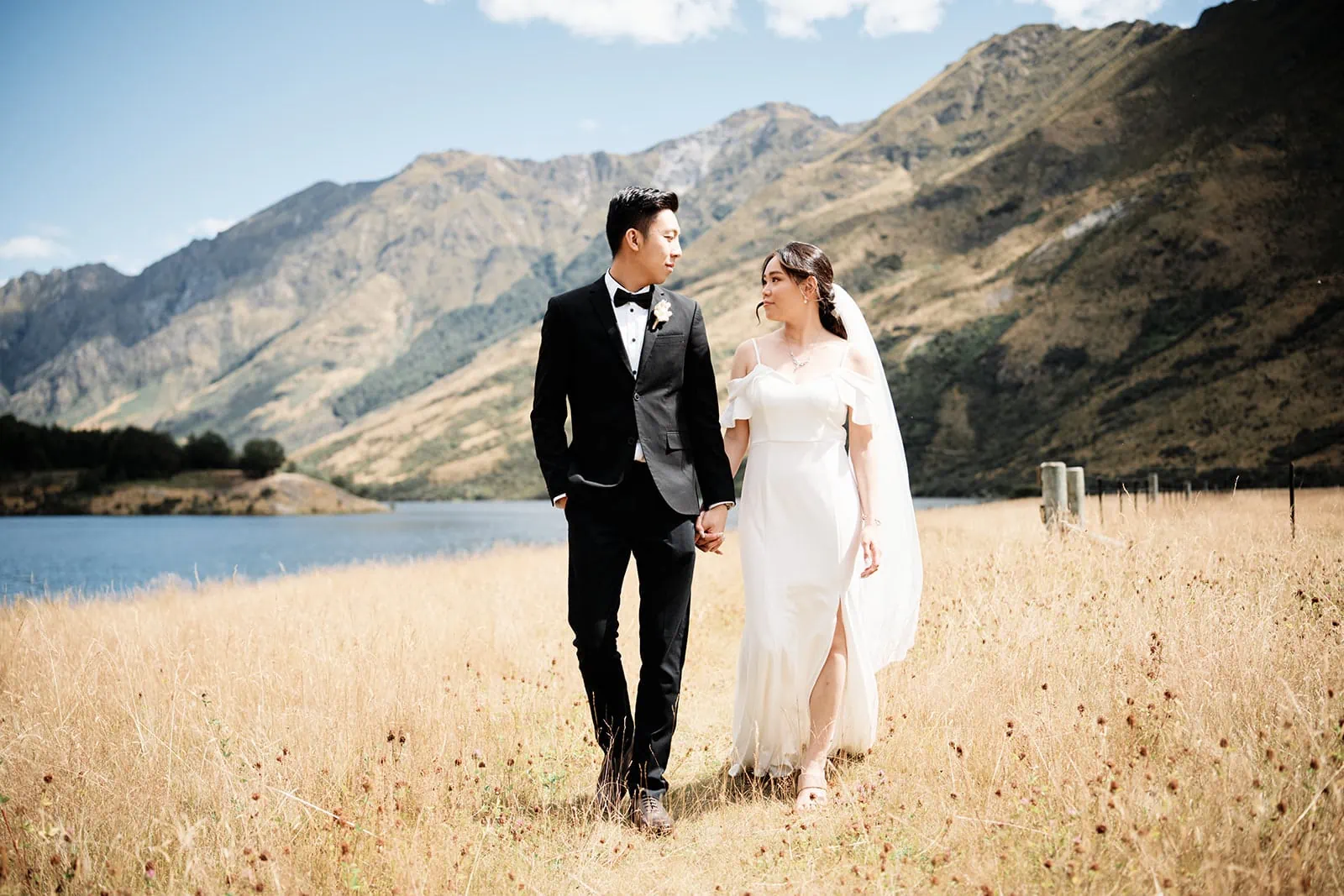 Dios and Carlyn at Cecil Peak, Queenstown - a couple standing in a field near a lake for their stunning pre-wedding photoshoot.