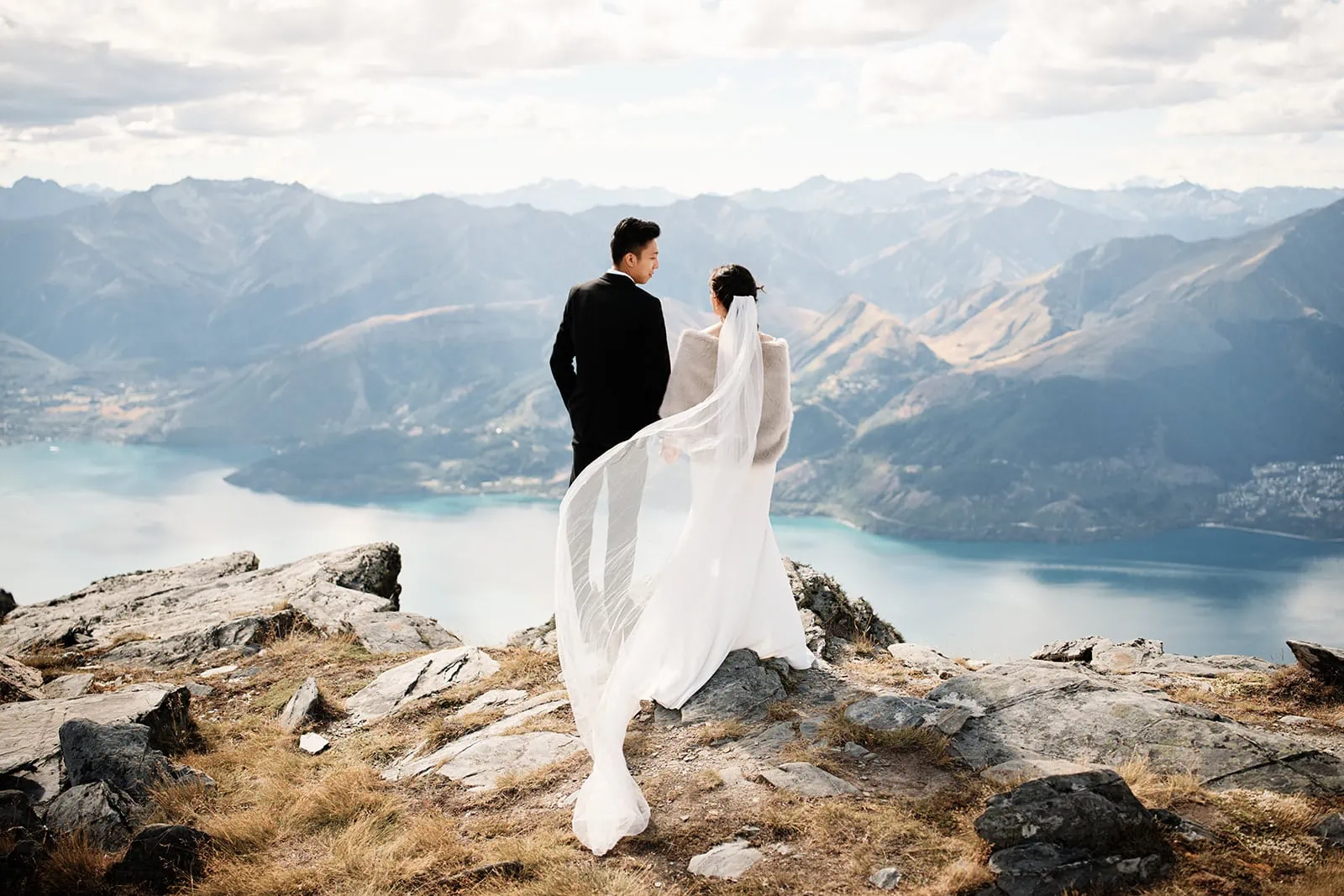 Bride and groom mountaintop overlook Wanaka lake.