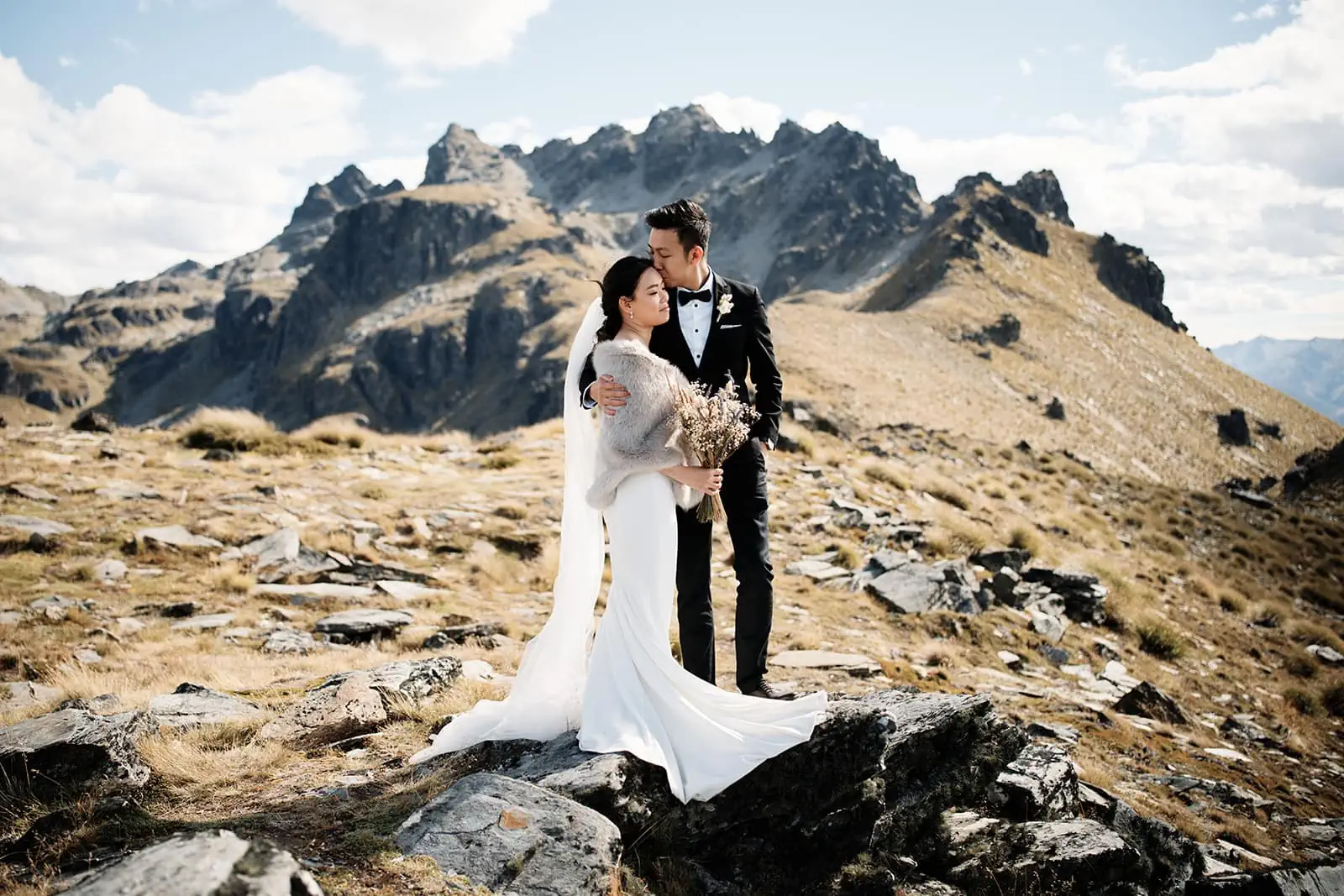A couple, Dios & Carlyn, standing on top of Cecil Peak in Queenstown, New Zealand for their heli pre-wedding shoot.