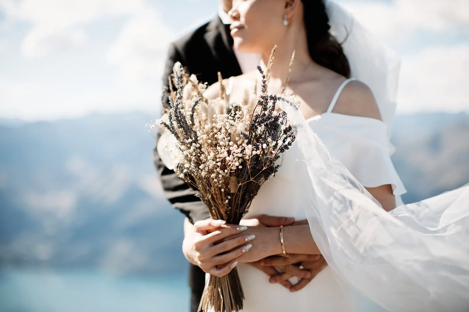 Dios & Carlyn's Queenstown Heli Pre Wedding showcases a bride and groom on top of Cecil Peak holding a bouquet.