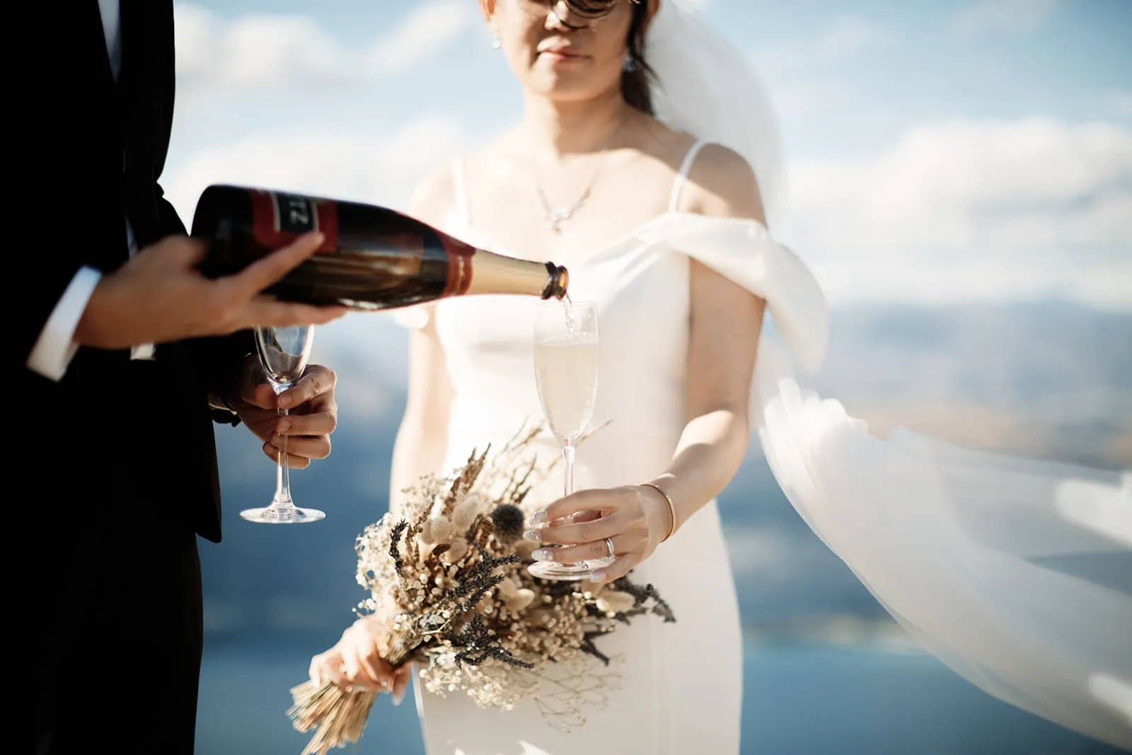 Dios and Carlyn celebrating their Queenstown Heli Pre Wedding with champagne on Cecil Peak.