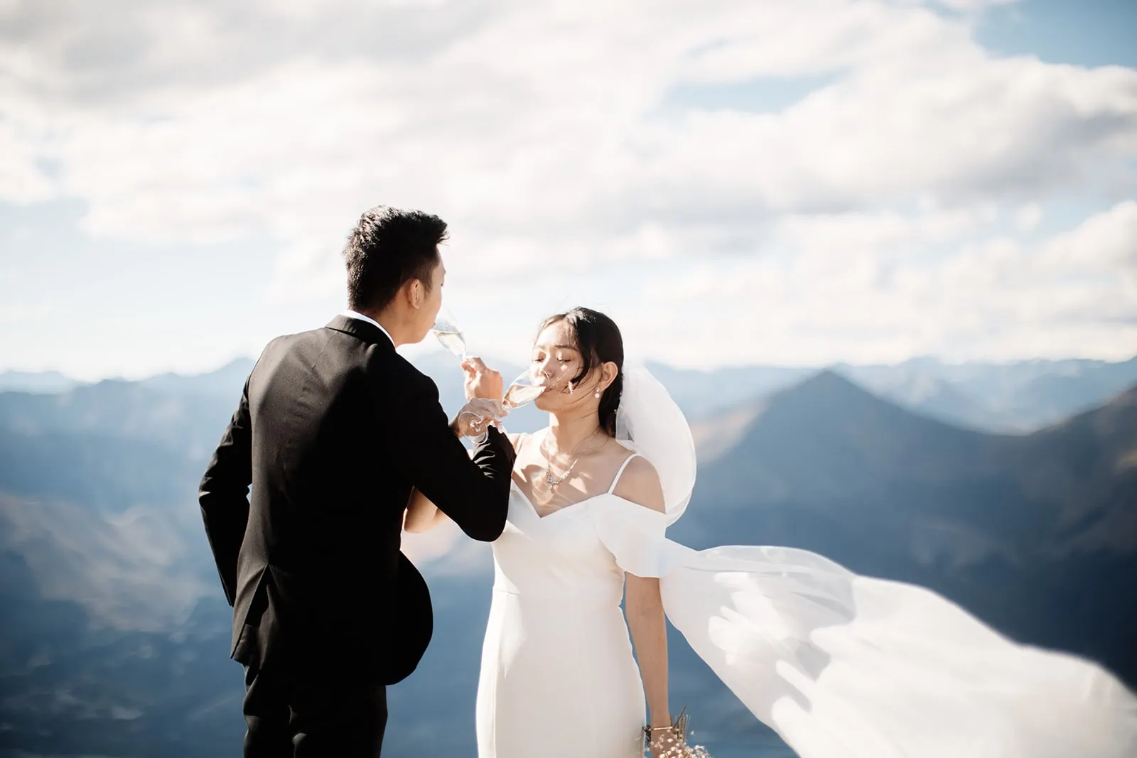 A scenic pre-wedding photoshoot featuring Dios and Carlyn atop Cecil Peak in Queenstown, where they joyfully feed each other cake.