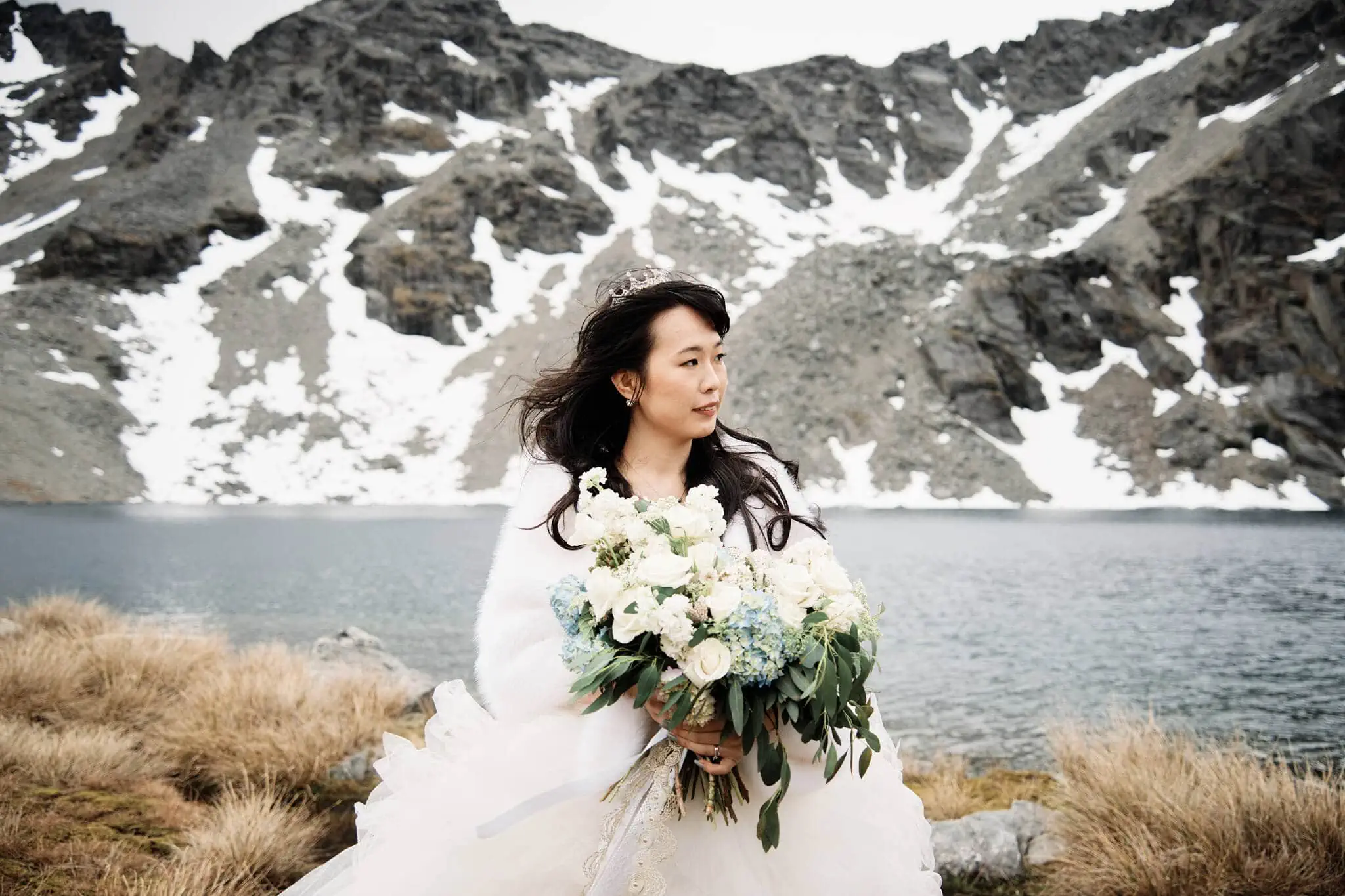 Carlos and Wanzhu's intimate elopement wedding at Cecil Peak with a bride holding a bouquet in front of a lake.