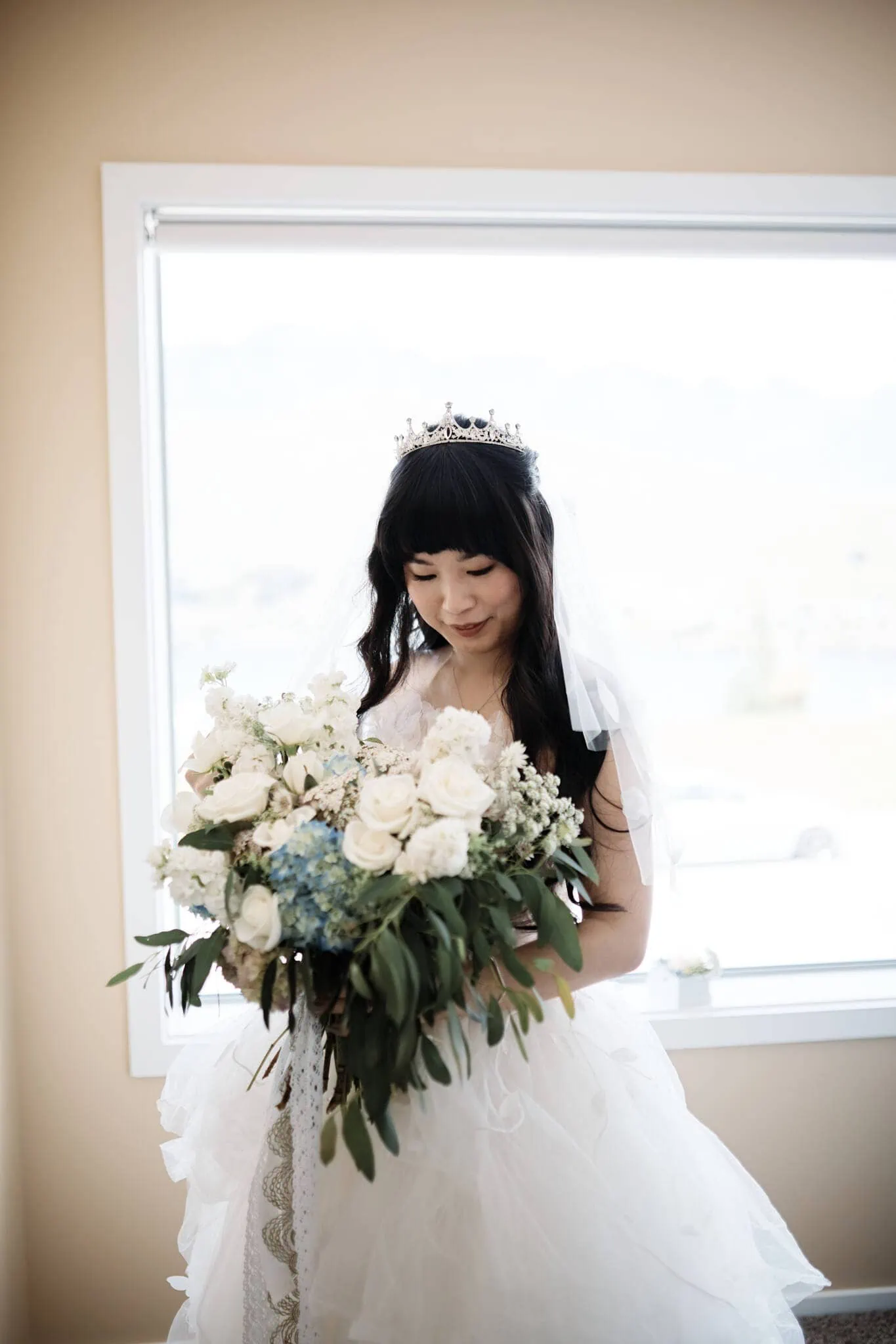 Intimate wedding ceremony with Carlos and Wanzhu at Cecil Peak, featuring a bride holding a bouquet in front of a window.