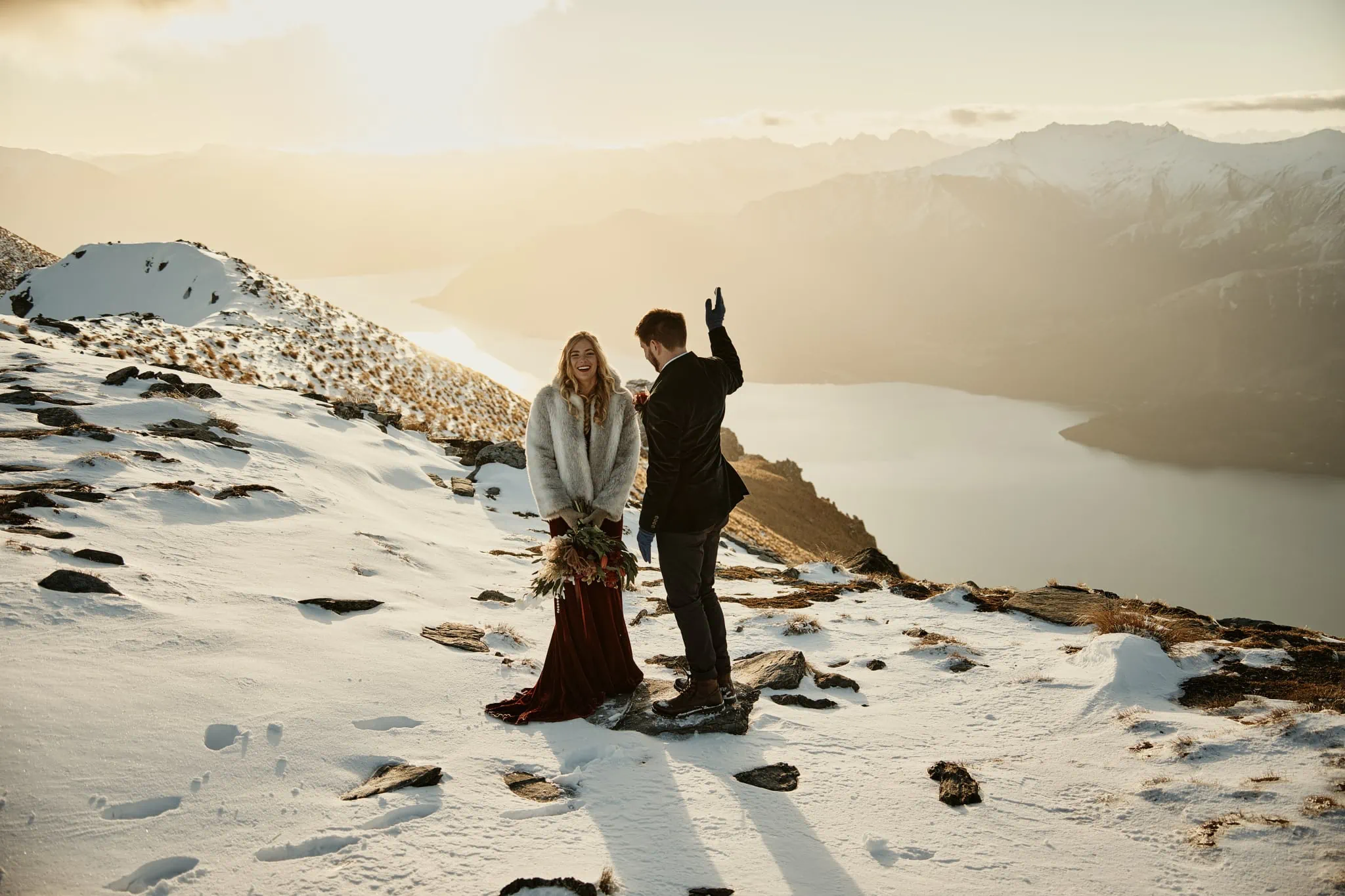 Claire and Rob's heli elopement wedding at Cecil Peak, with a bride and groom standing on top of a snowy mountain overlooking Lake Wanaka.