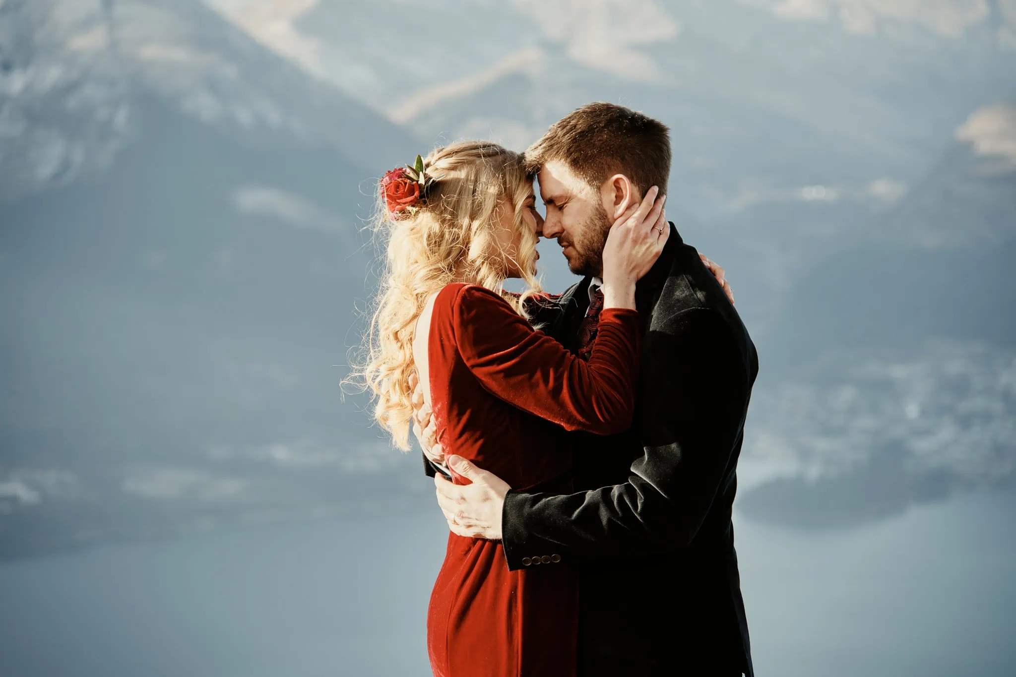 Claire and Rob's heli elopement wedding at Cecil Peak in Switzerland, with a couple embracing on top of a mountain.