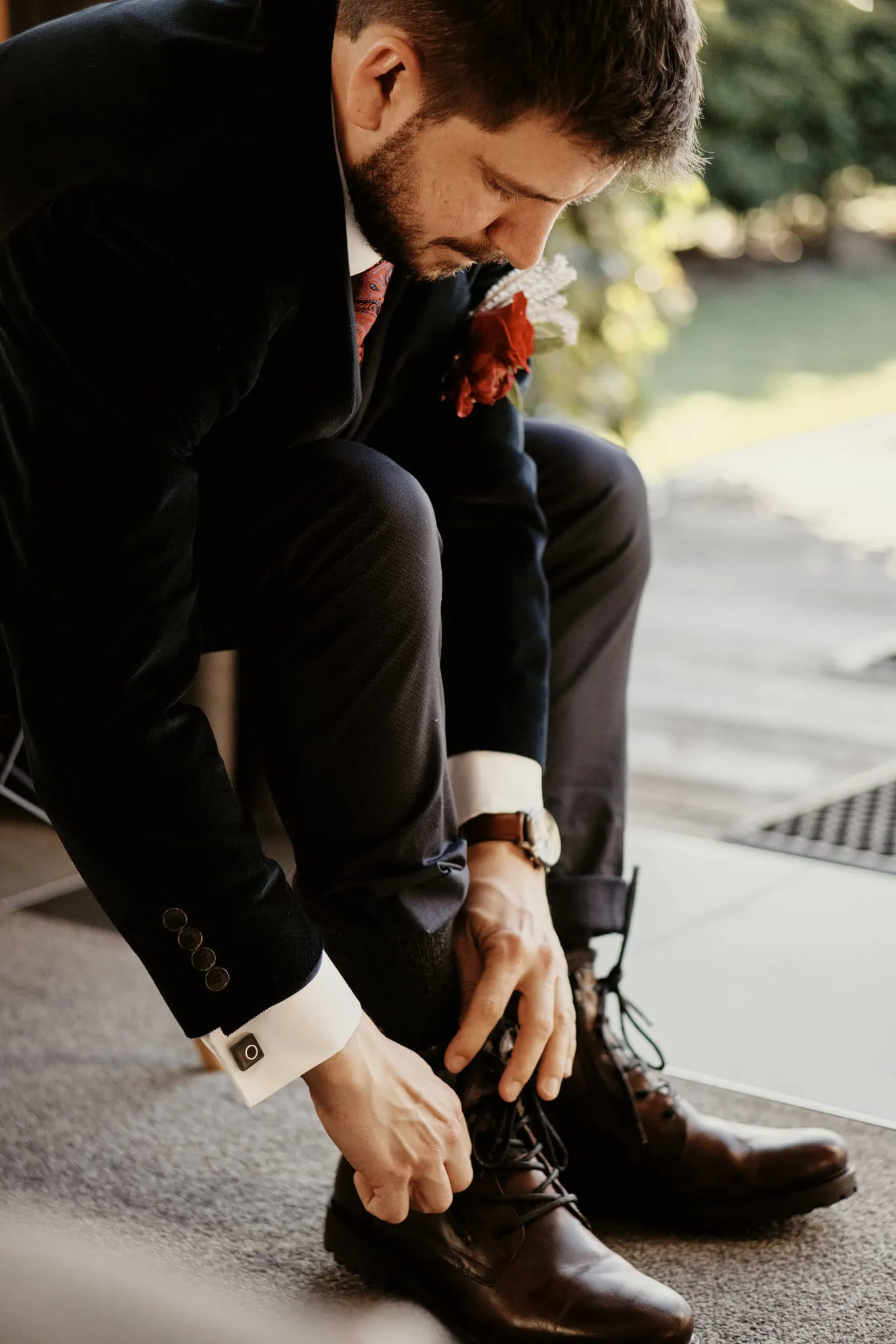 A man in a suit tying his shoes at Claire and Rob's Heli Elopement Wedding at Cecil Peak.