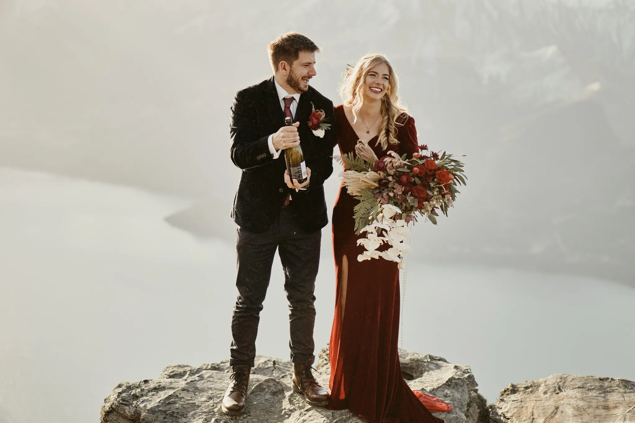 Claire and Rob celebrating their heli elopement wedding atop Cecil Peak with champagne.