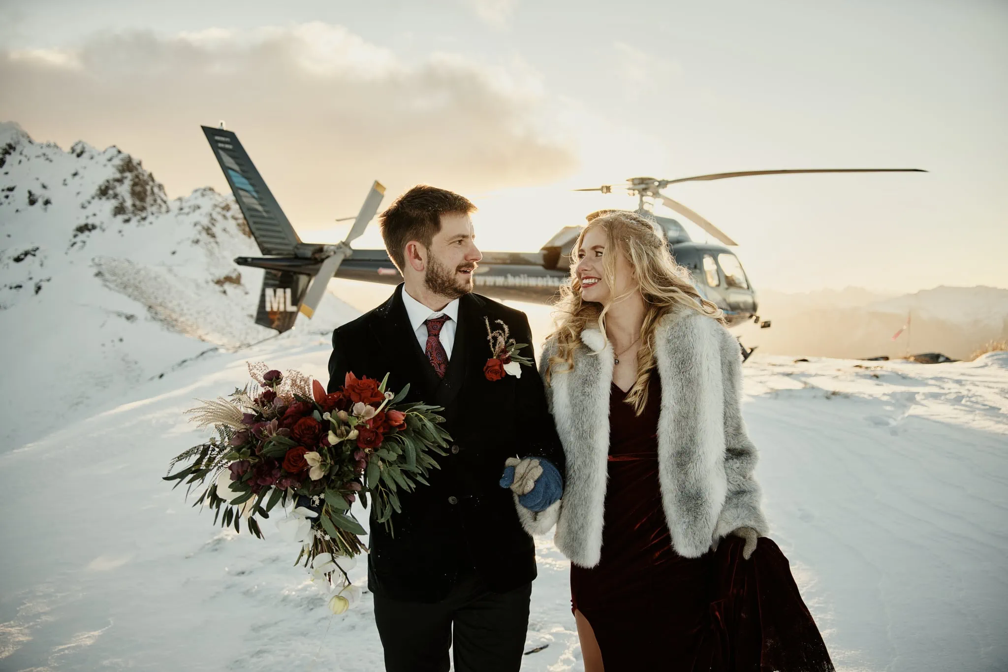 Claire and Rob's heli elopement wedding at Cecil Peak captures a bride and groom standing in front of a helicopter.