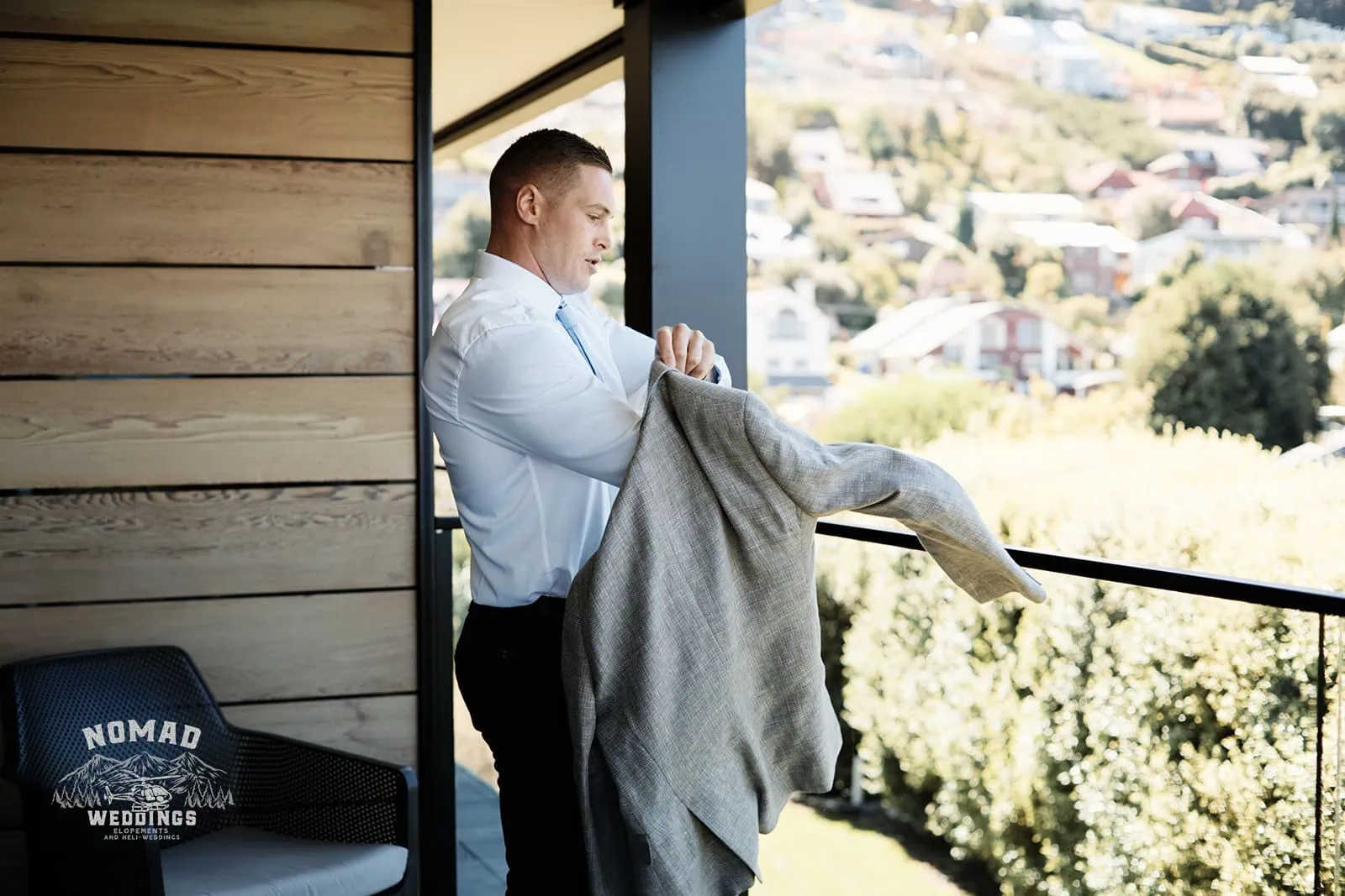 A man in a suit standing on a balcony during an enchanting Lake Erskine elopement.
