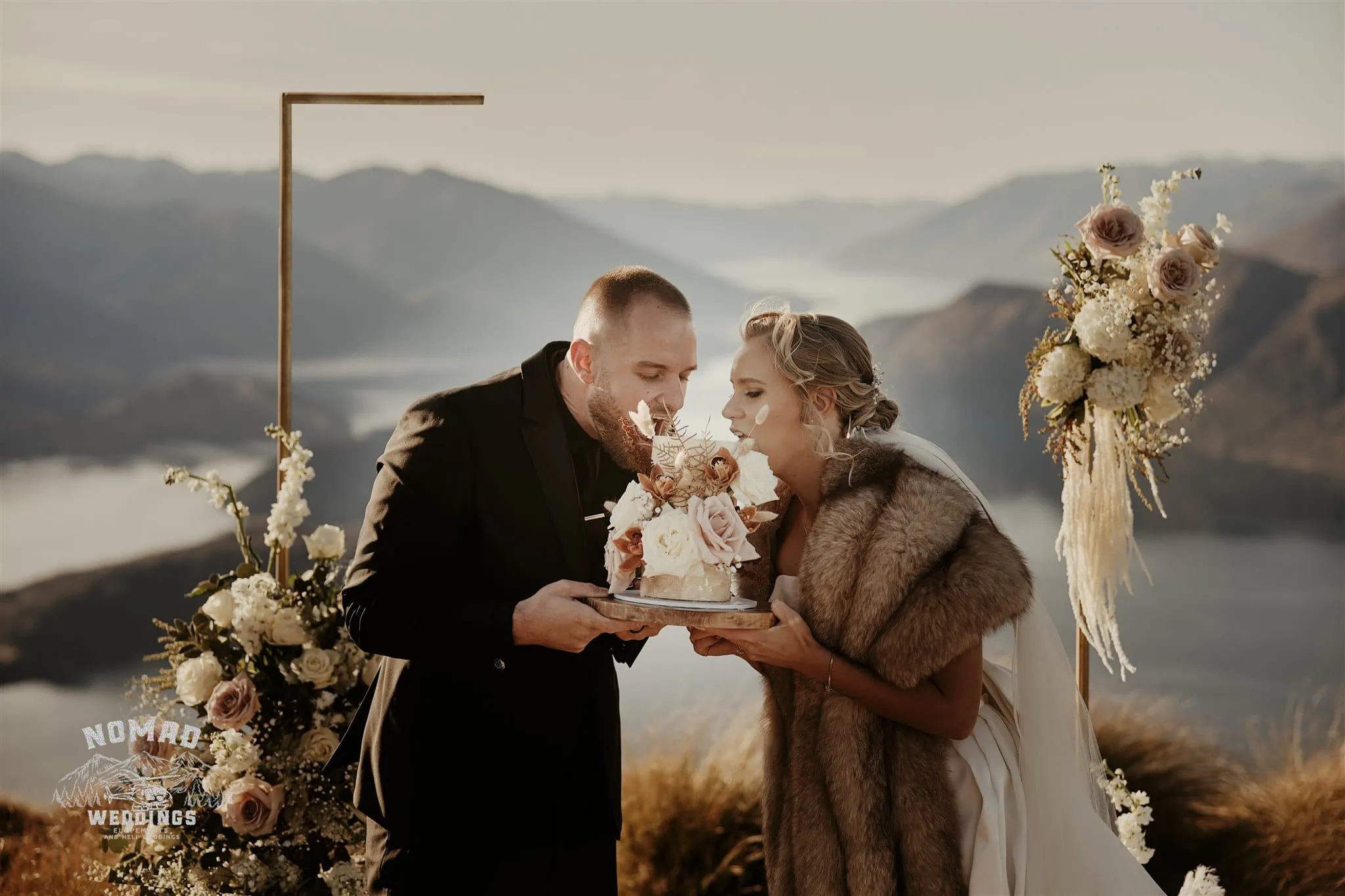 Jay and Dave celebrate their Coromandel Peak Heli Elopement Wedding by sharing a cake on top of a mountain in New Zealand.