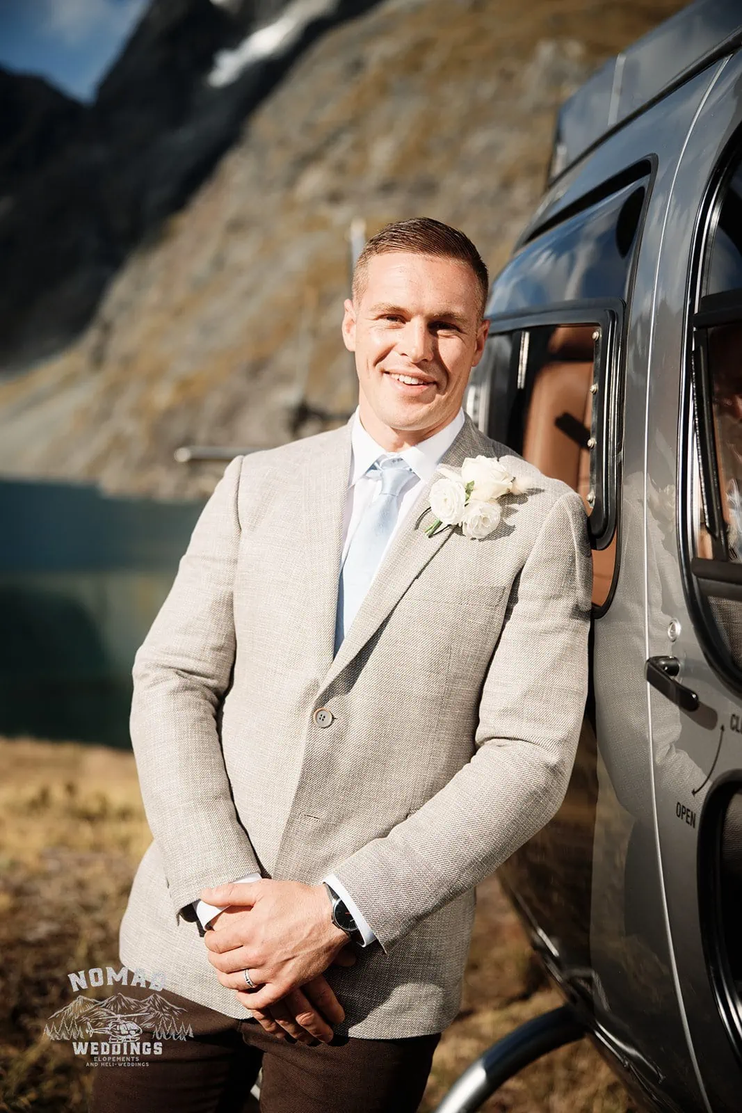 A groom standing in front of a Enchanting Lake Erskine helicopter.