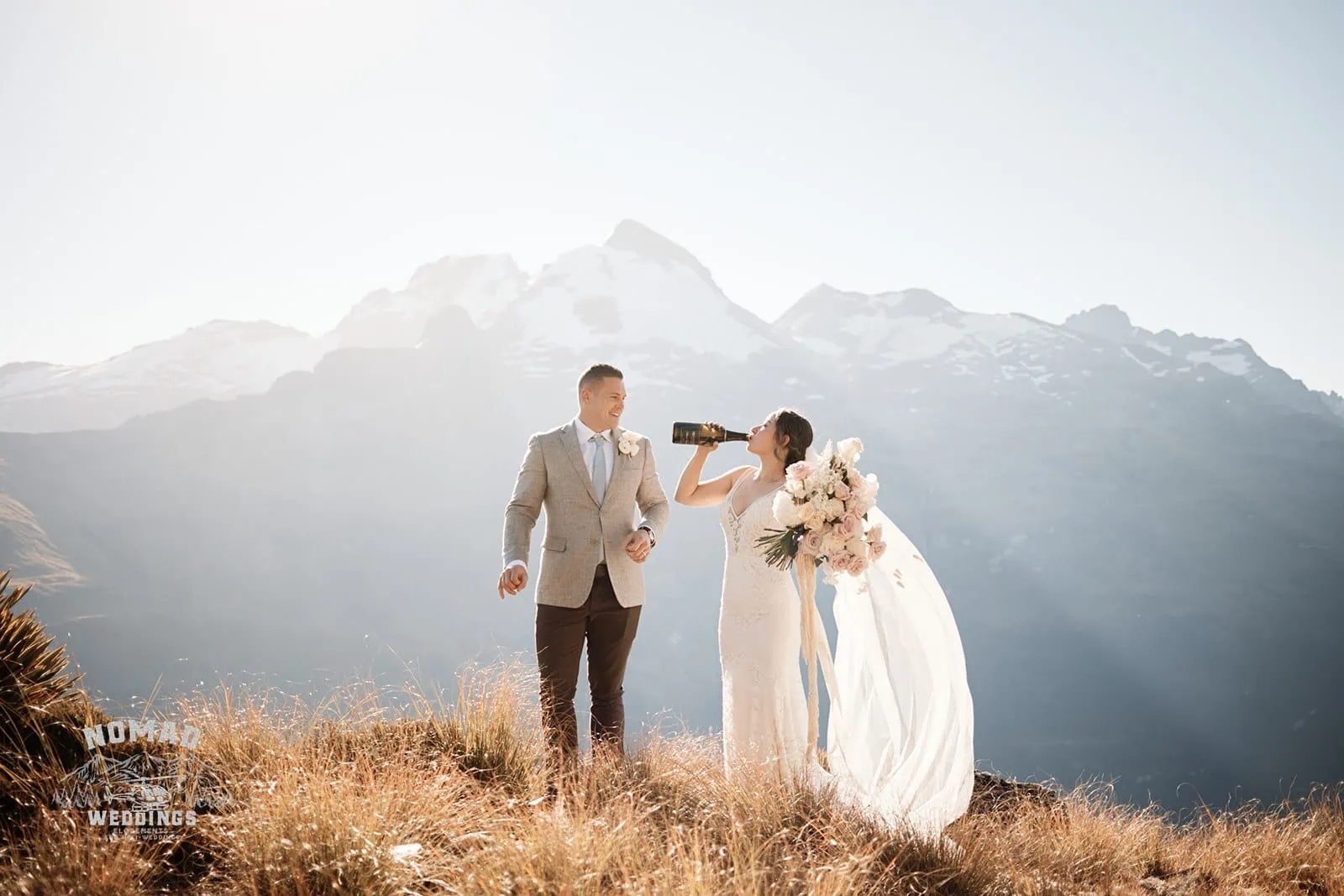 Amy & Eden standing on top of a hill with enchanting mountains in the background | Lake Erskine elopement.