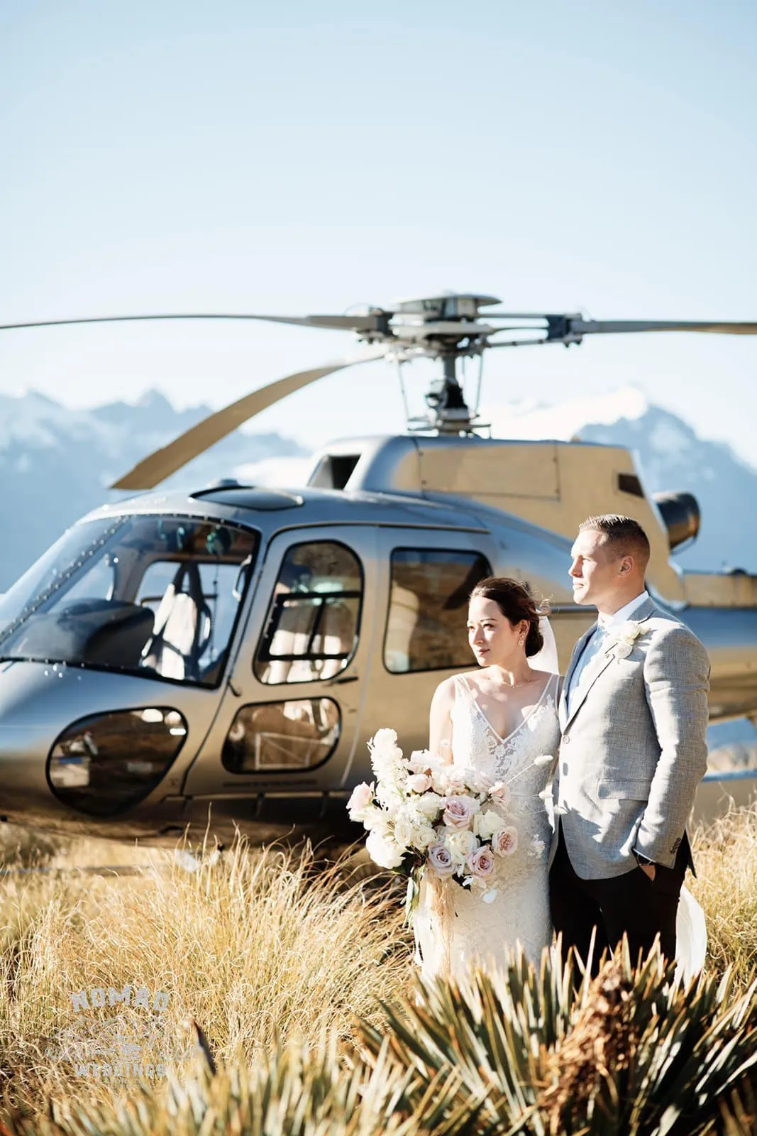 Amy and Eden's enchanting Lake Erskine heli elopement wedding, with a bride and groom standing in front of a helicopter.