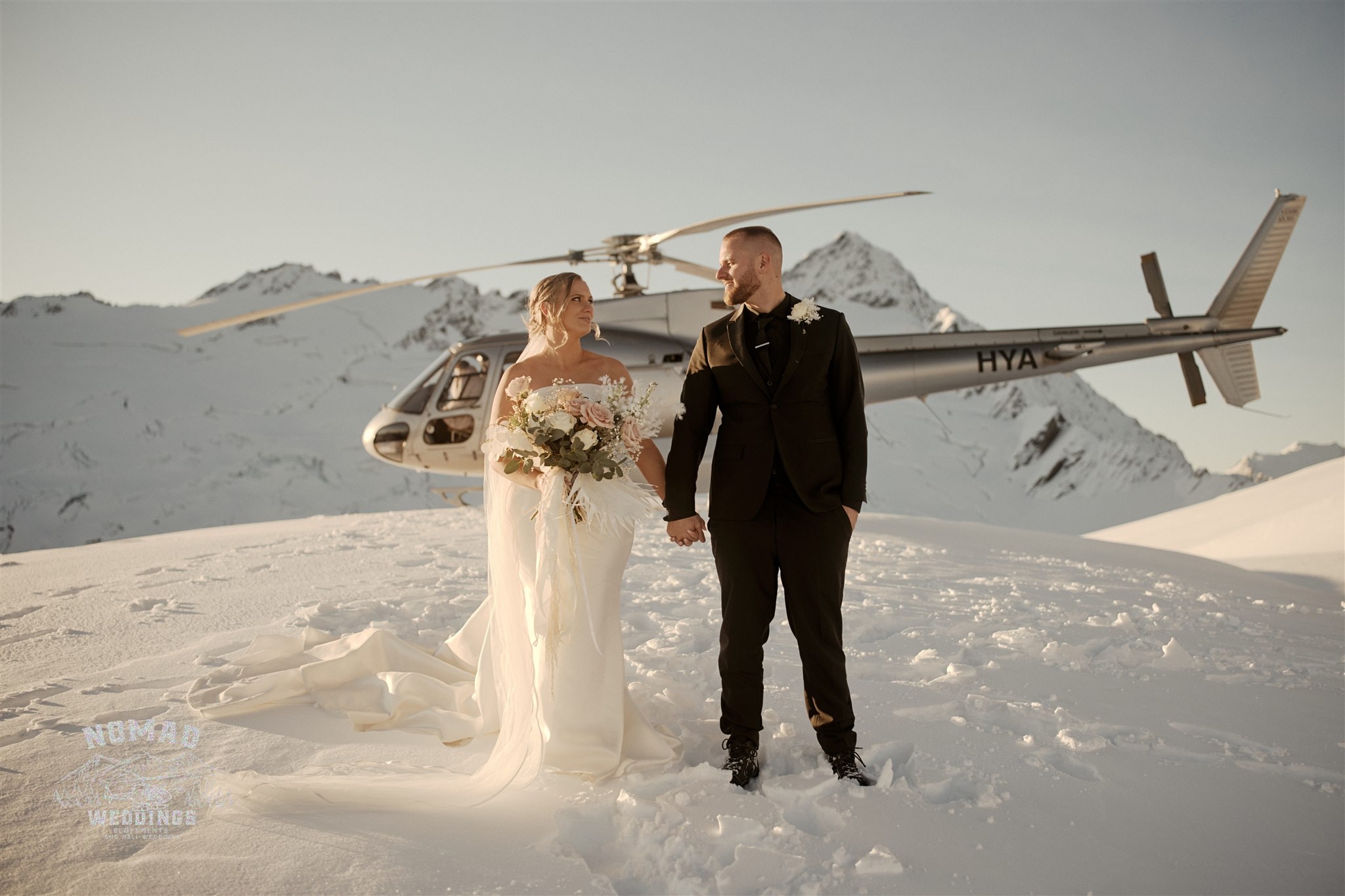 Jay and Dave's Coromandel Peak Heli Elopement Wedding features a bride and groom standing in front of a helicopter.
