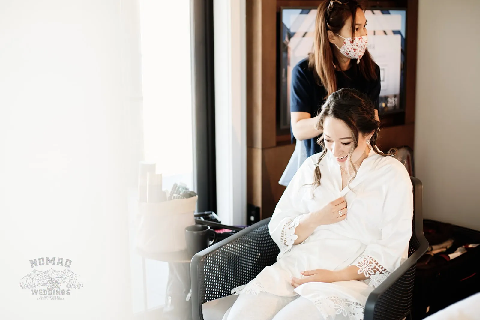 A woman getting her hair done in a hotel room for an enchanting wedding.