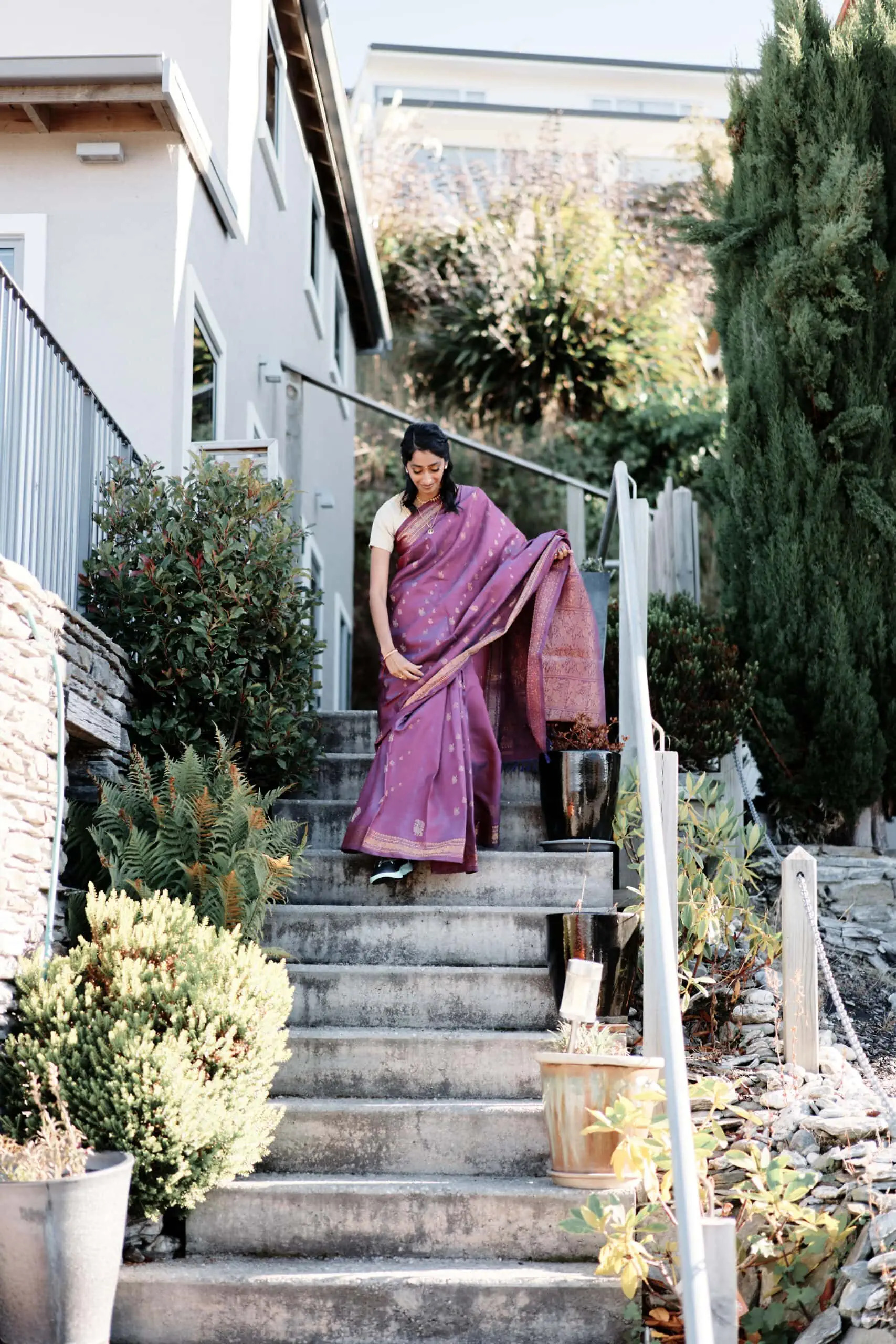 A woman in a purple sari is walking up a set of stairs.
