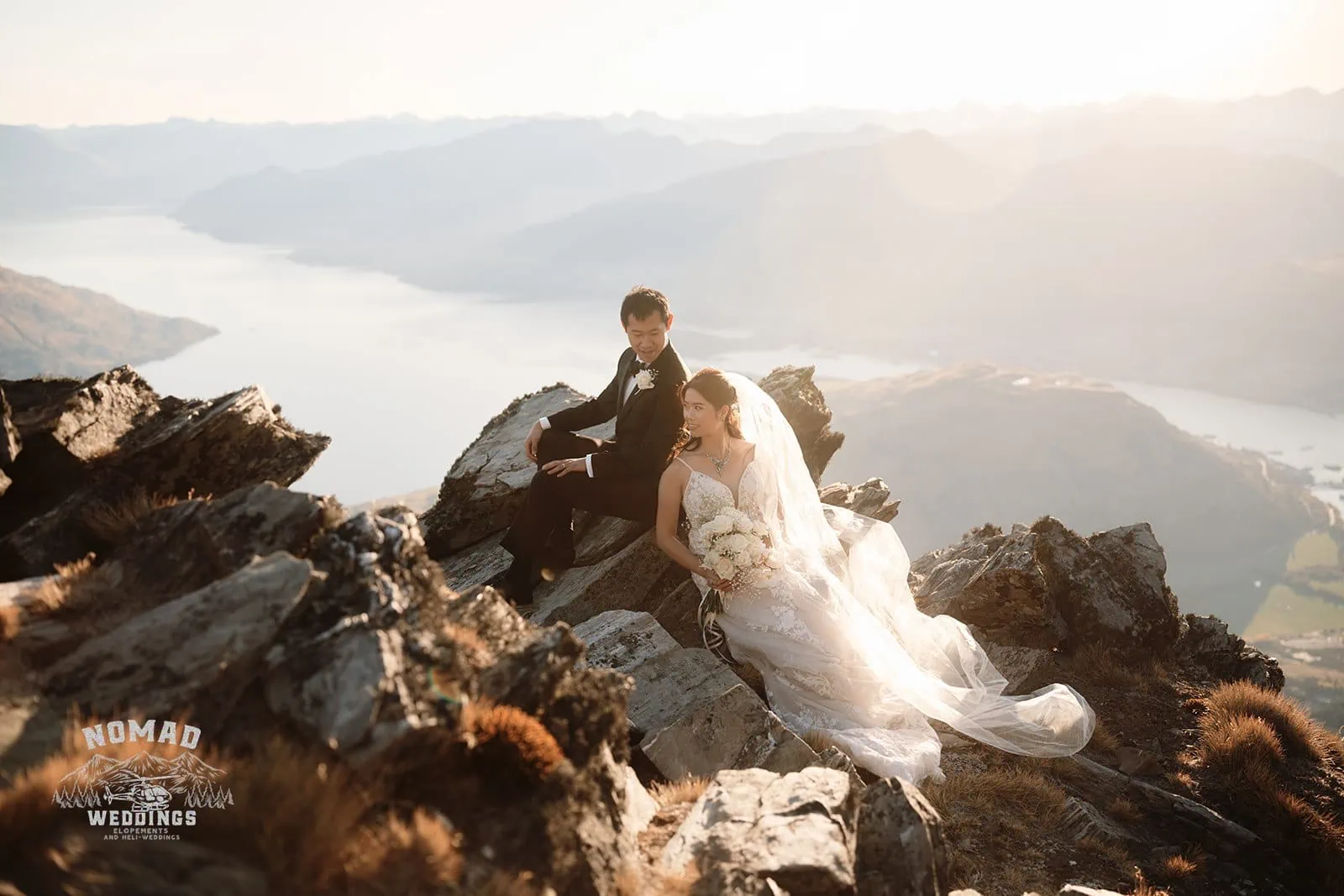 Connie and Andrew enjoying a Remarkables Heli Pre Wedding Shoot on top of a mountain overlooking Lake Wanaka.