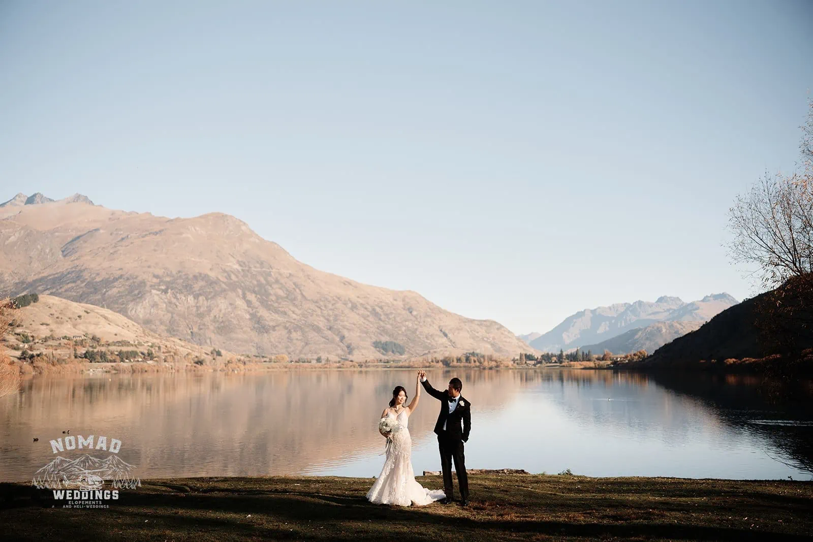Connie and Andrew standing in front of The Remarkables lake during their Heli Pre Wedding Shoot.