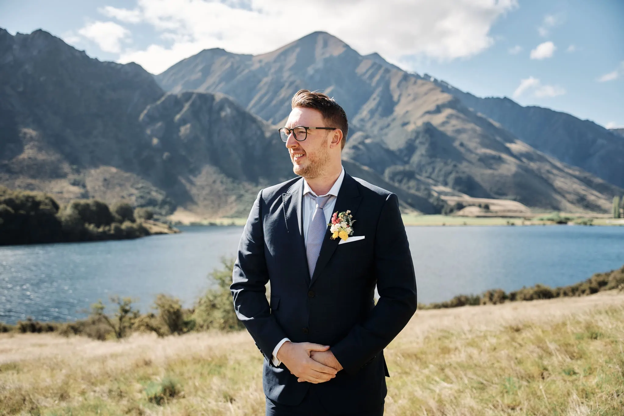 A groom, Ace, standing in front of Moke Lake with mountains in the background during his pre-wedding shoot.