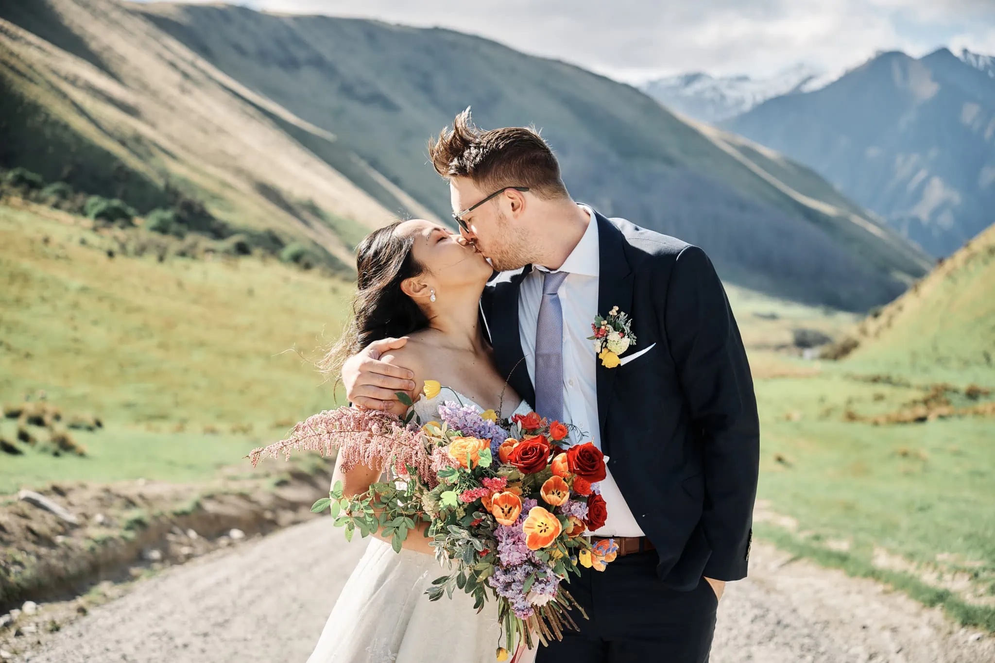 Ace and Alex share a romantic kiss on a dirt road during their Moke Lake pre-wedding shoot in the mountains.